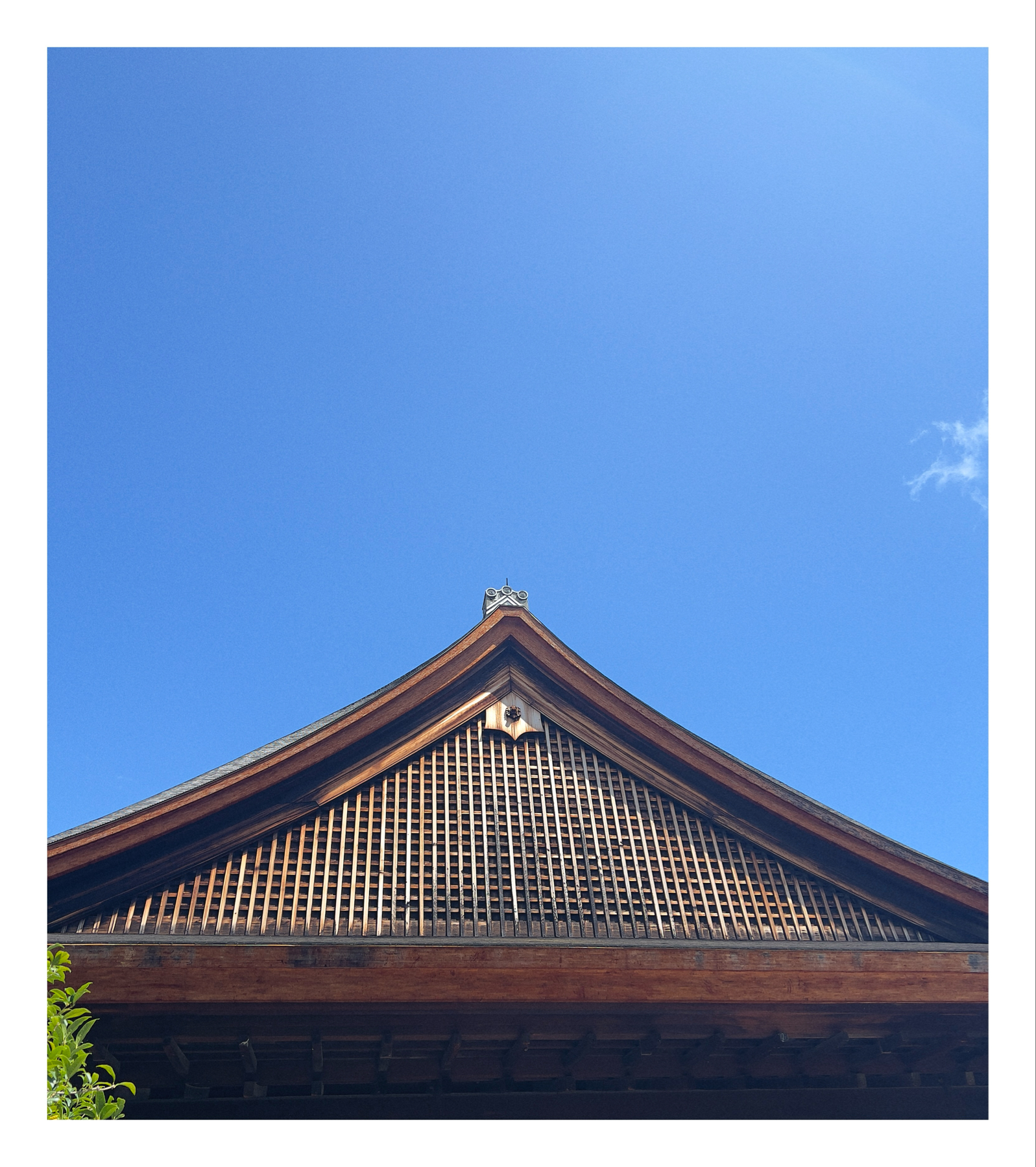 A traditional Japanese building rooftop against a clear blue sky.