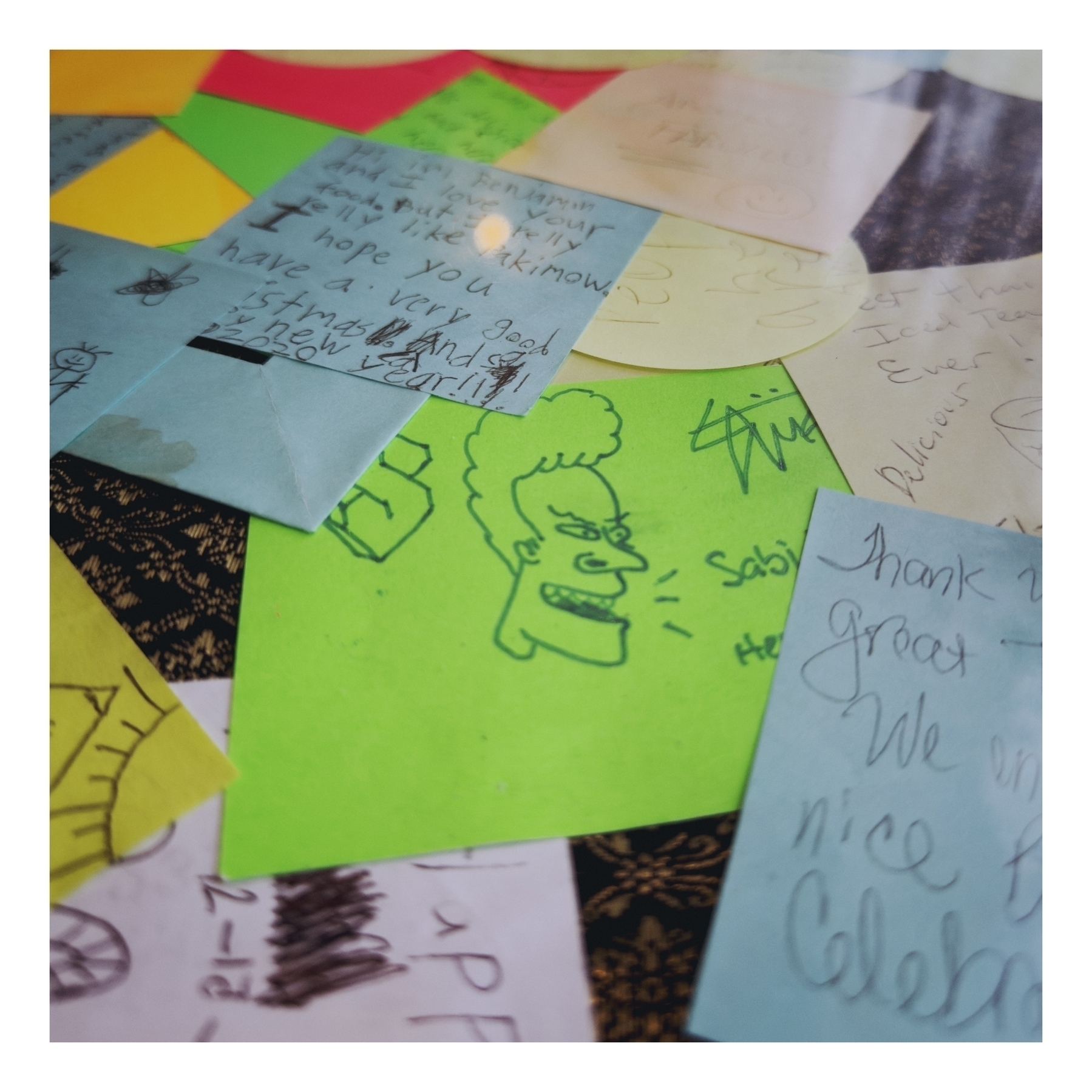 A collection of colorful sticky notes with handwritten messages, drawings, and signatures, scattered on a surface. Some of the notes include words like “Thank you,” “Happy,” and “Best Thai Iced Tea.” There is also an illustration resembling a cartoon of Beavis, and a cool S. 