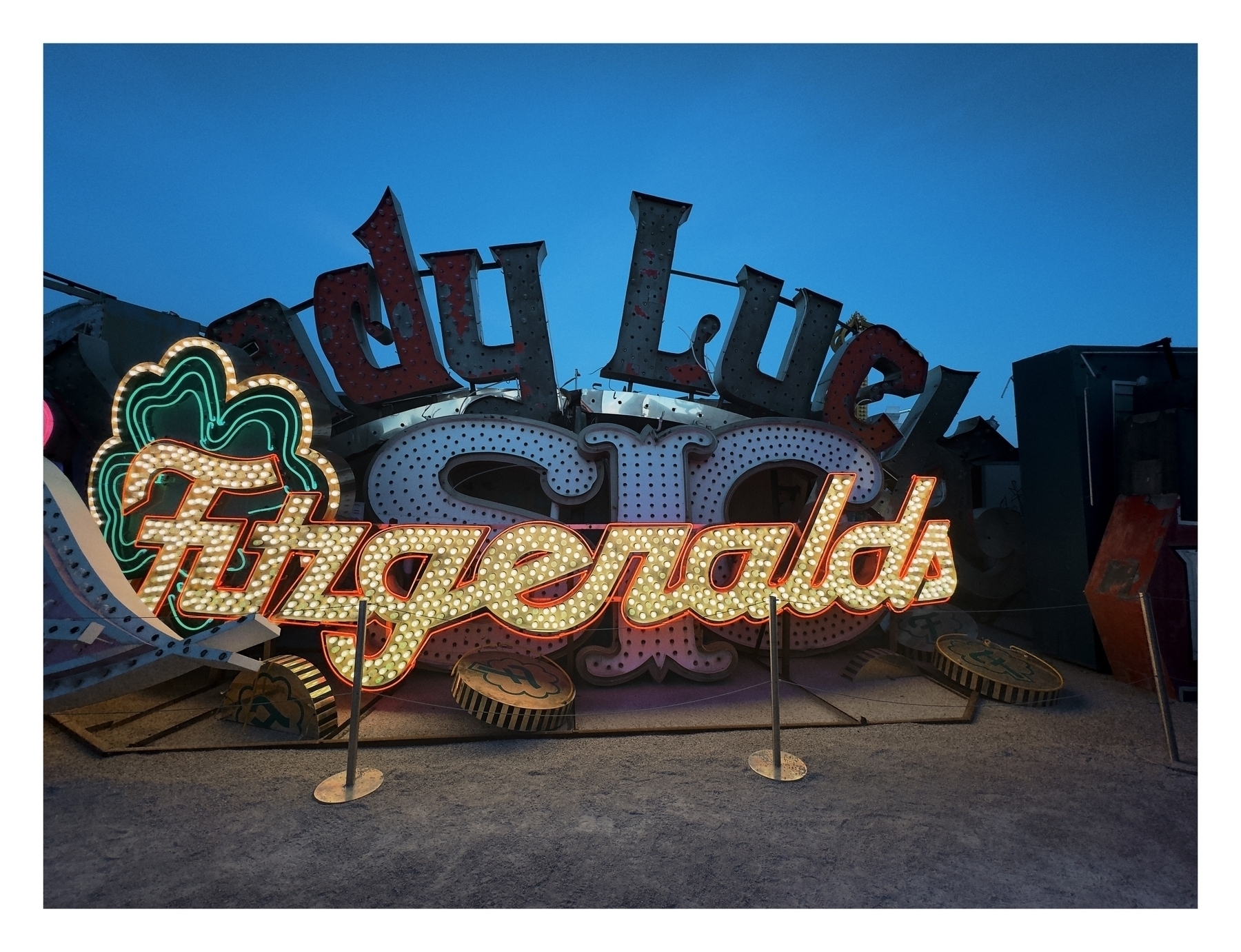 Vintage neon signs reading “Lady Luck” and “Fitzgeralds” stand against a twilight sky, implying a retro or decommissioned setting.