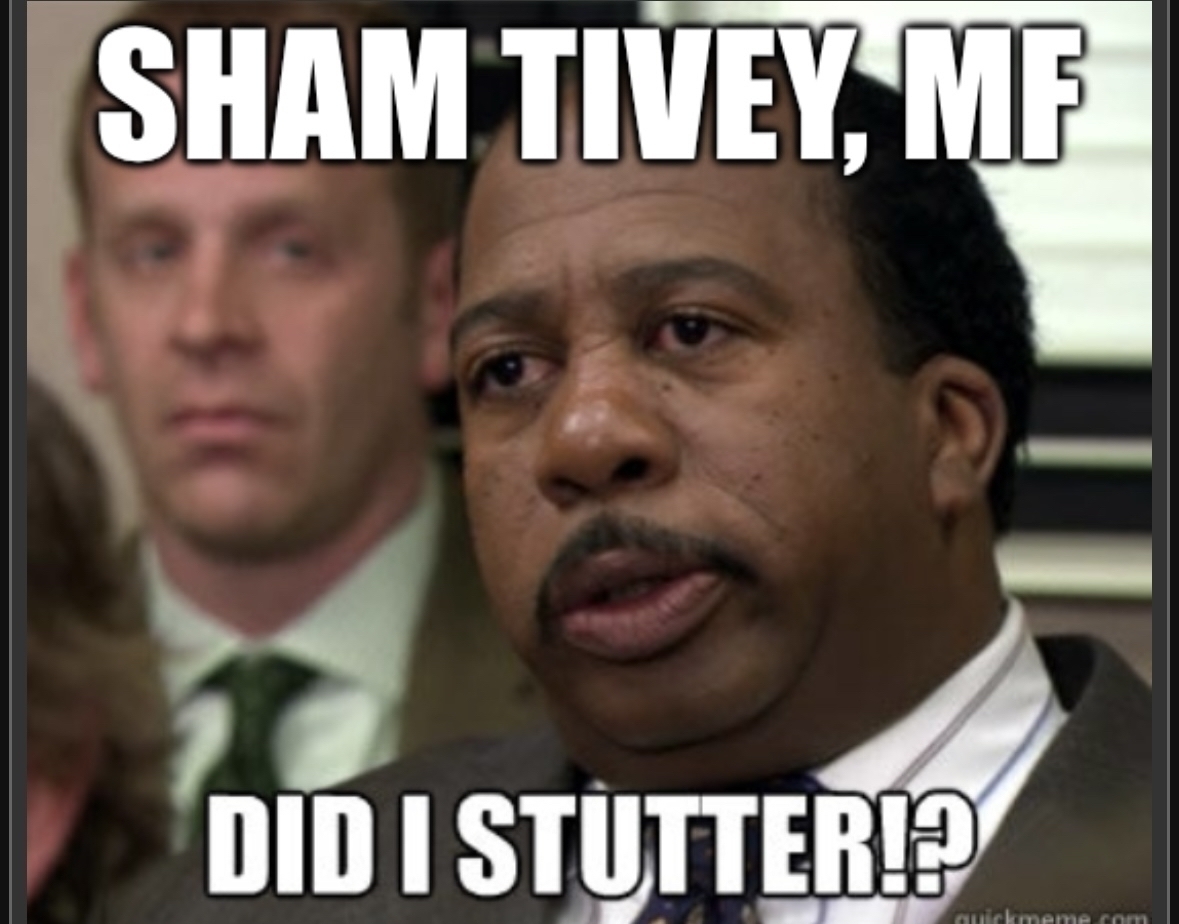 A man appears skeptical or confrontational, with a caption above reading “SHAM TIVEY, MF” and below “DID I STUTTER?” in an office setting.