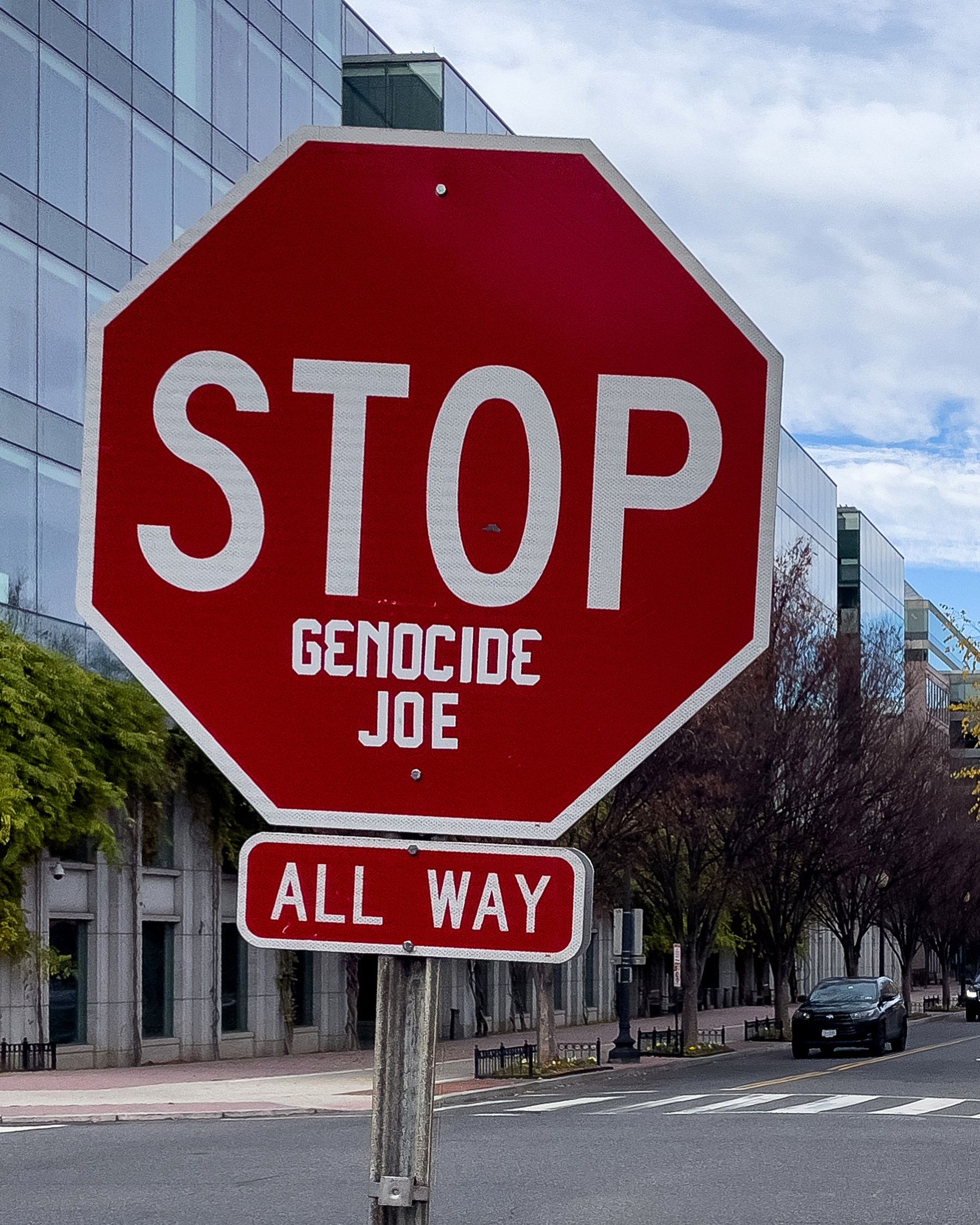 A photo of a stop sign, located in Capitol Hill, Washington, D.C., which is stenciled in a fashion  so that it reads “STOP GENOCIDE JOE”.