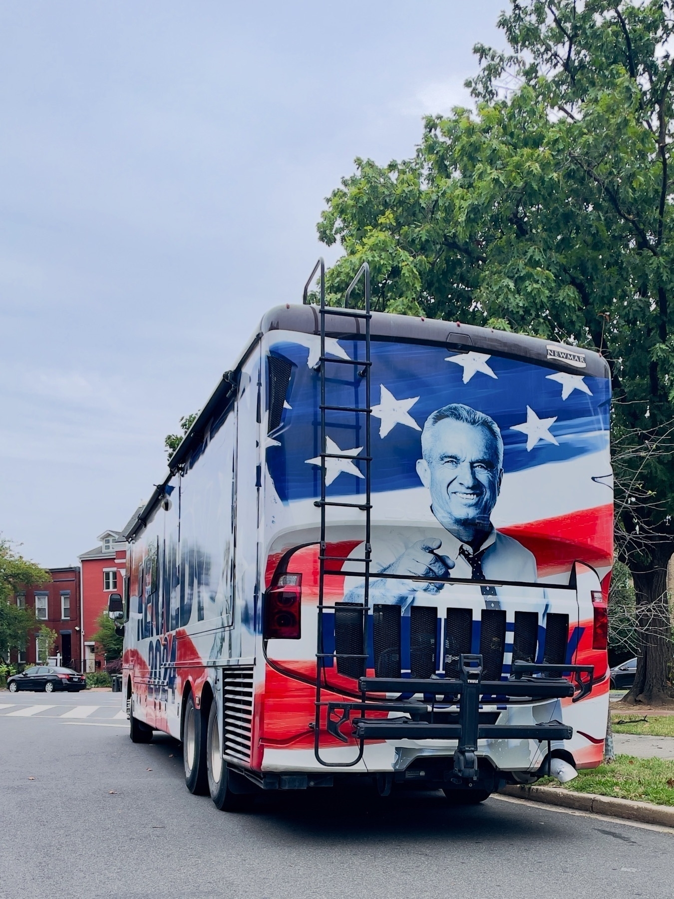 A photograph of the RFK Jr “Kennedy 2024” bus, seen from the rear left, parked (illegally) in DC.