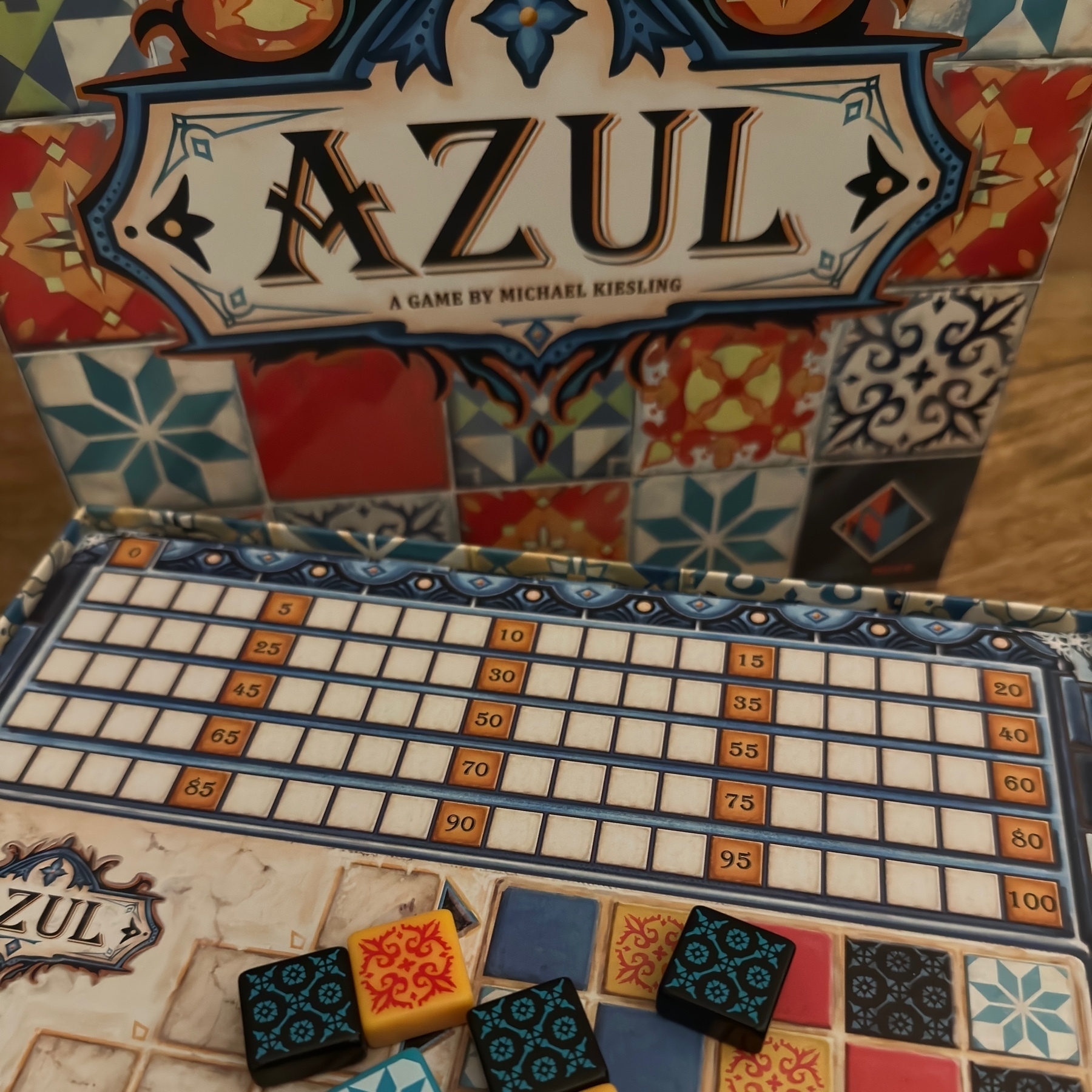 tiles from the boardgame Azul in front of the game's box