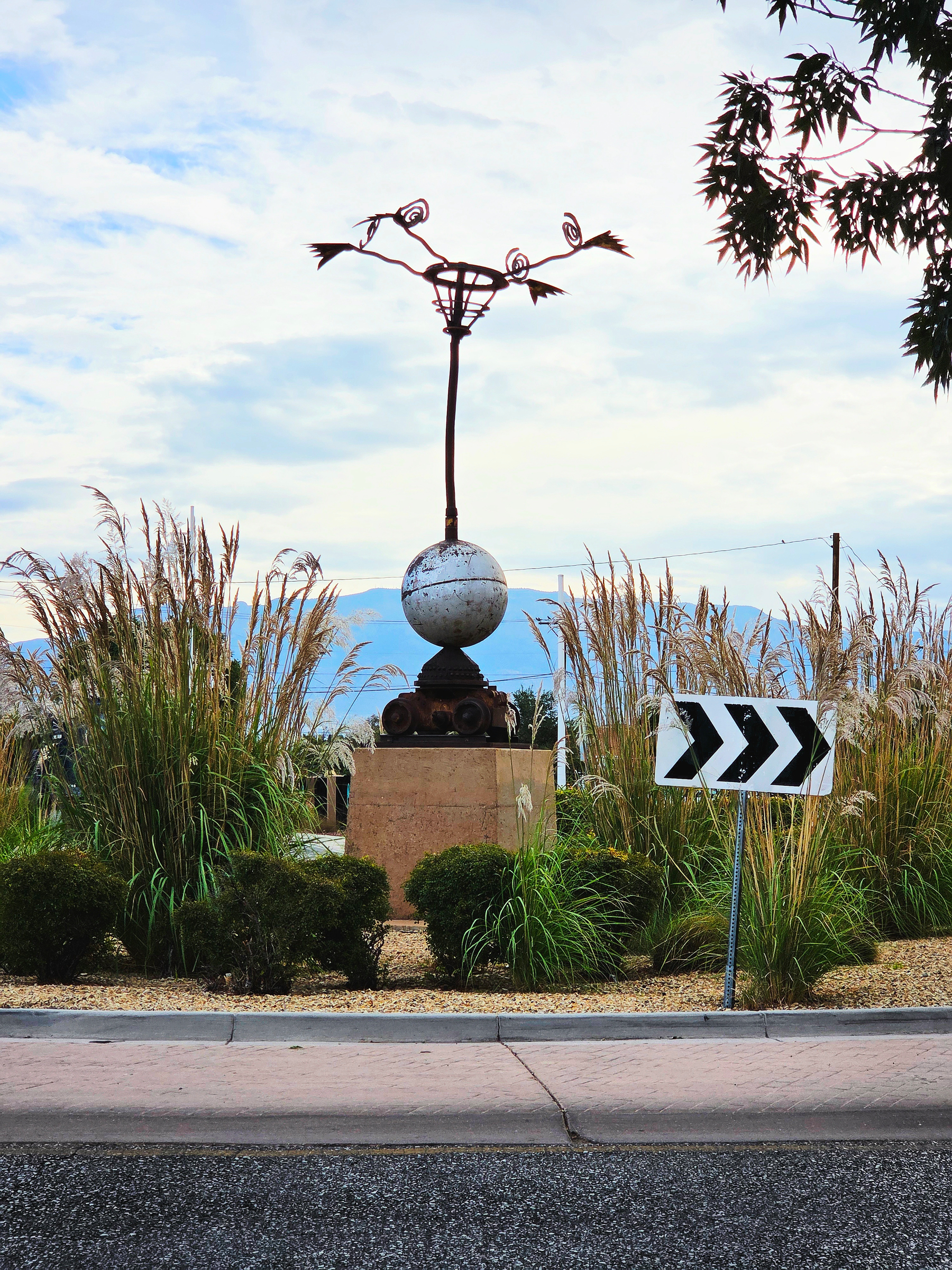 A whimsical metal sculpture rising above tall ornamental grass