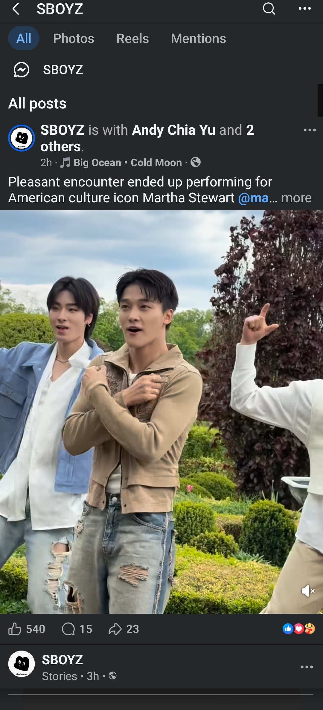 Auto-generated description: Three people are casually posing outdoors near a garden, one wearing a light blue jacket, another in a light brown jacket, and the third in a white shirt.