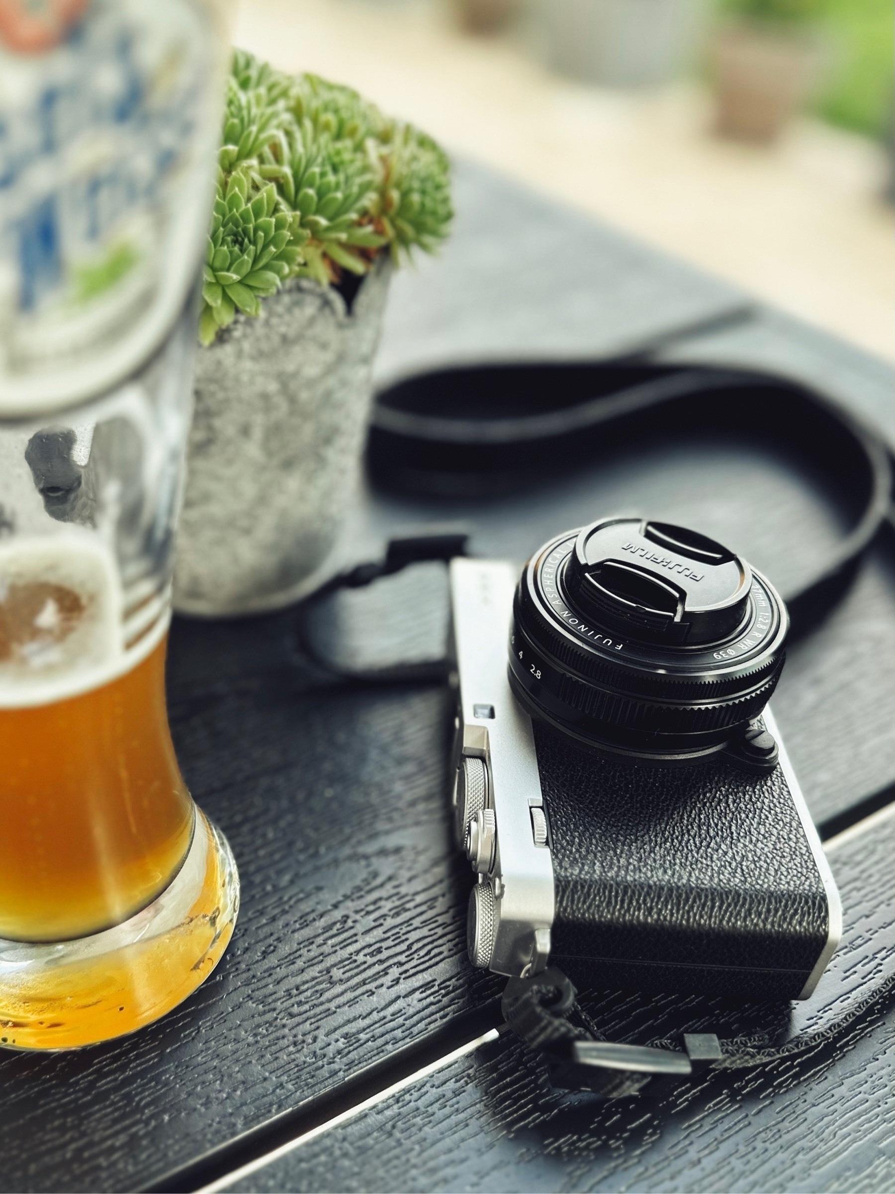 A camera lies on a table in the restaurant with a half-drunk wheat beer glass next to it.