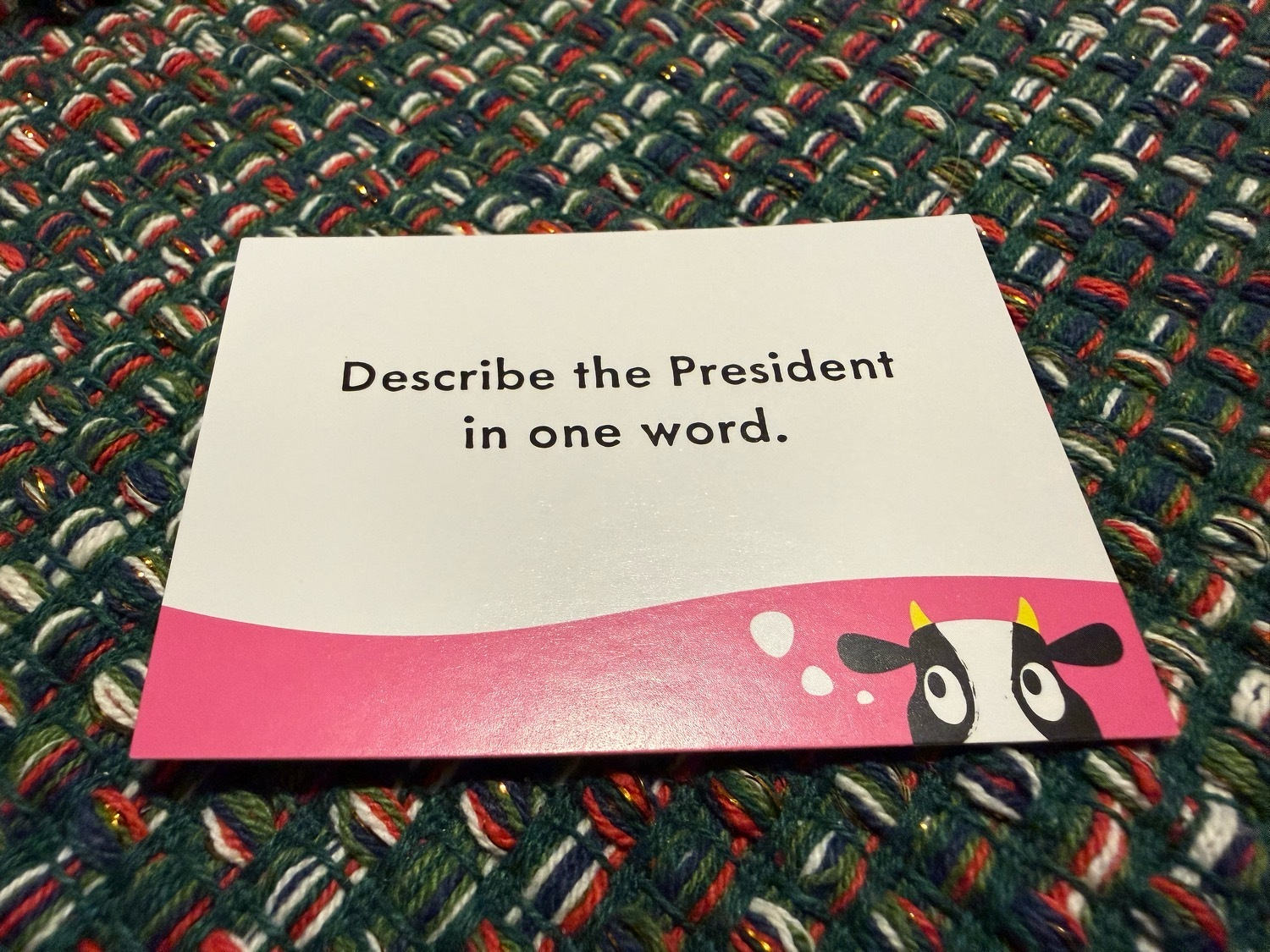 A game card saying “Describe the Predsident in one word”