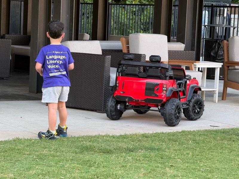 A kid steering a remote controlled Jeep that is as big as he is