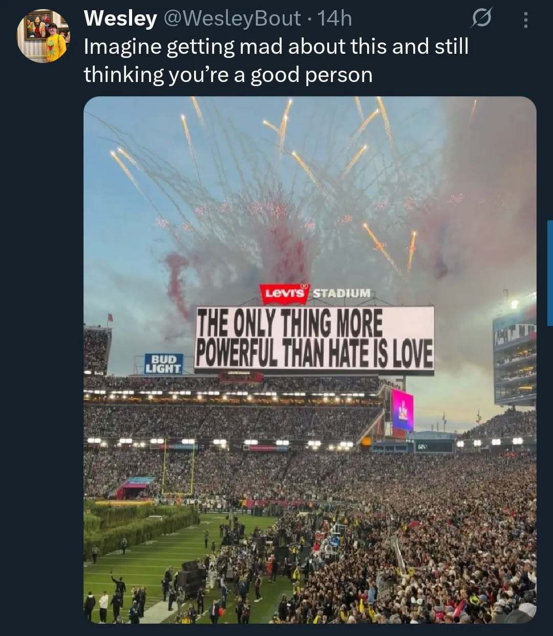 Screenshot of a social media post showing an image from the Super Bowl Halftime show where the stadium scoreboard says ”The only thing more powerful than hate is love.” The post says “Imagine getting mad about this and still thinking you’re a good person.”