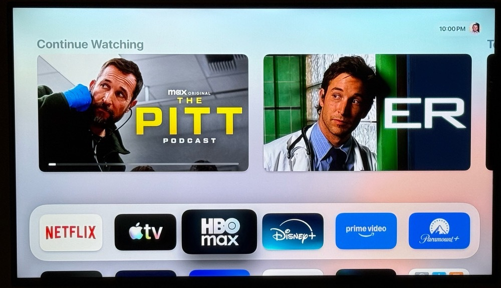 Screenshot of my AppleTV home screen showing the two most recent shows I watched from HBO, “The Pitt (Official Podcast” and “ER”, both showing pictures of Noah Wylie tilting his head in a promo photograph for the respective show.