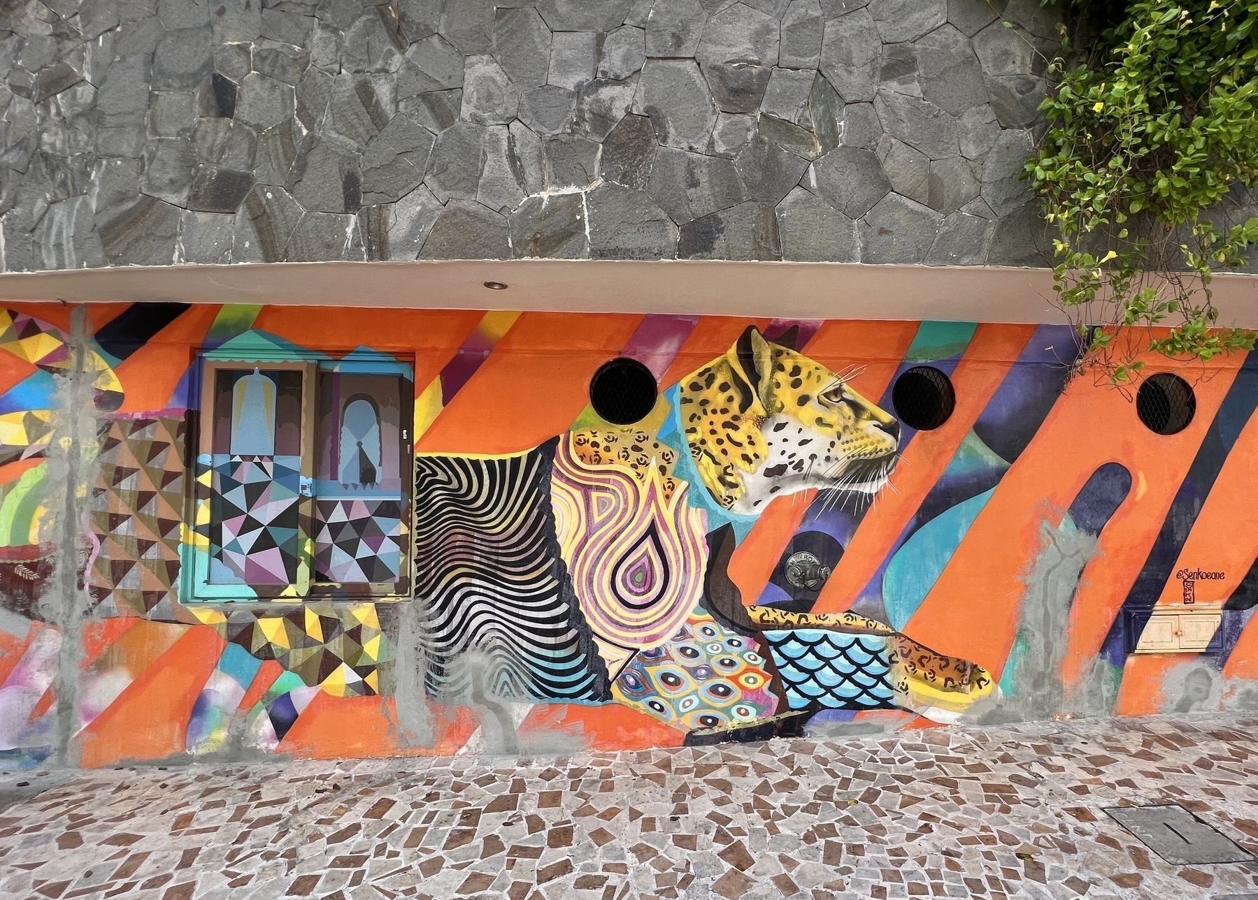 Street art in a Mexican style showing a jaguar head with a zebra body. 