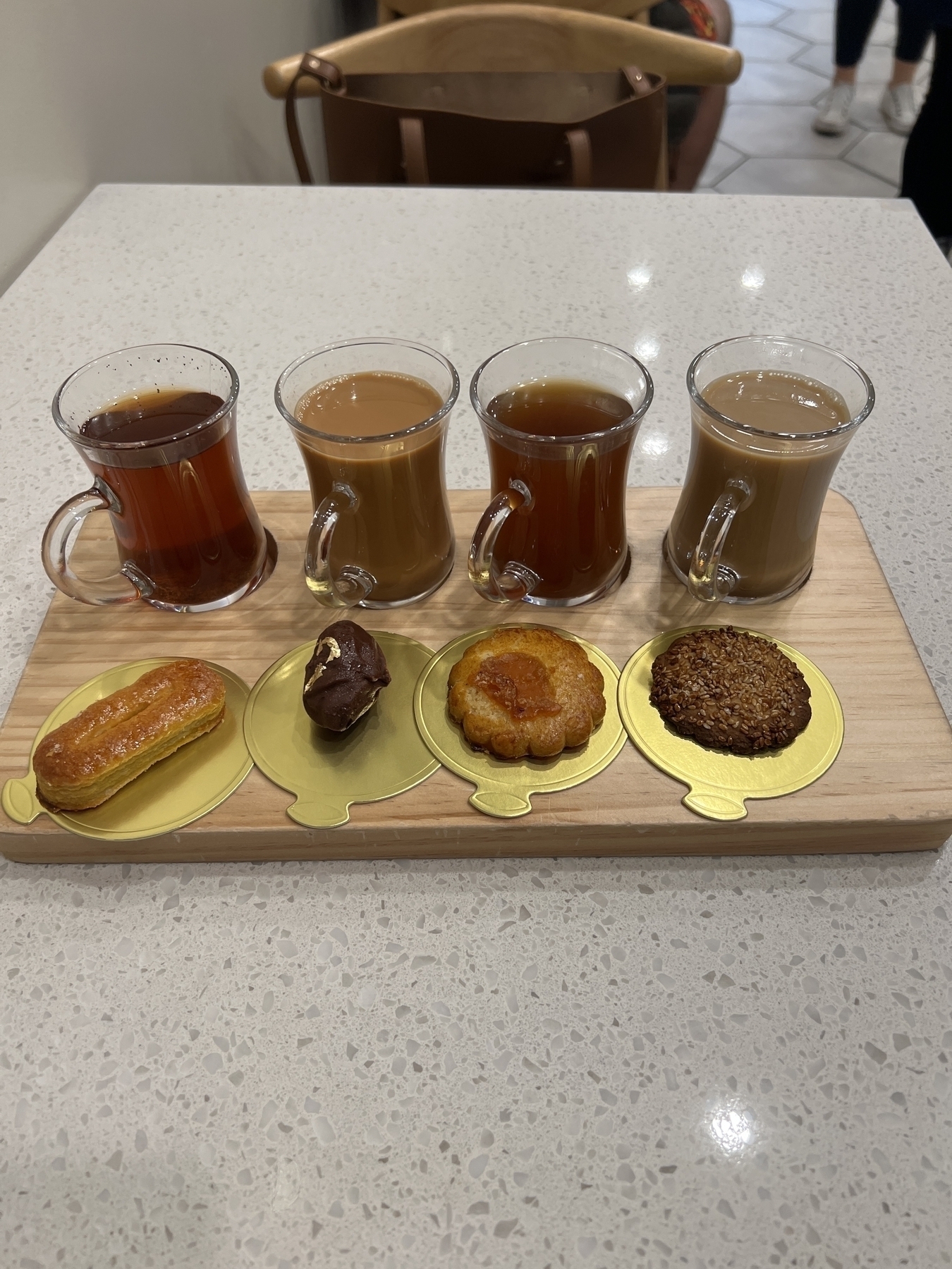 Assortment of beverages in glass cups. Pastries in foreground on wooden serving platter. 