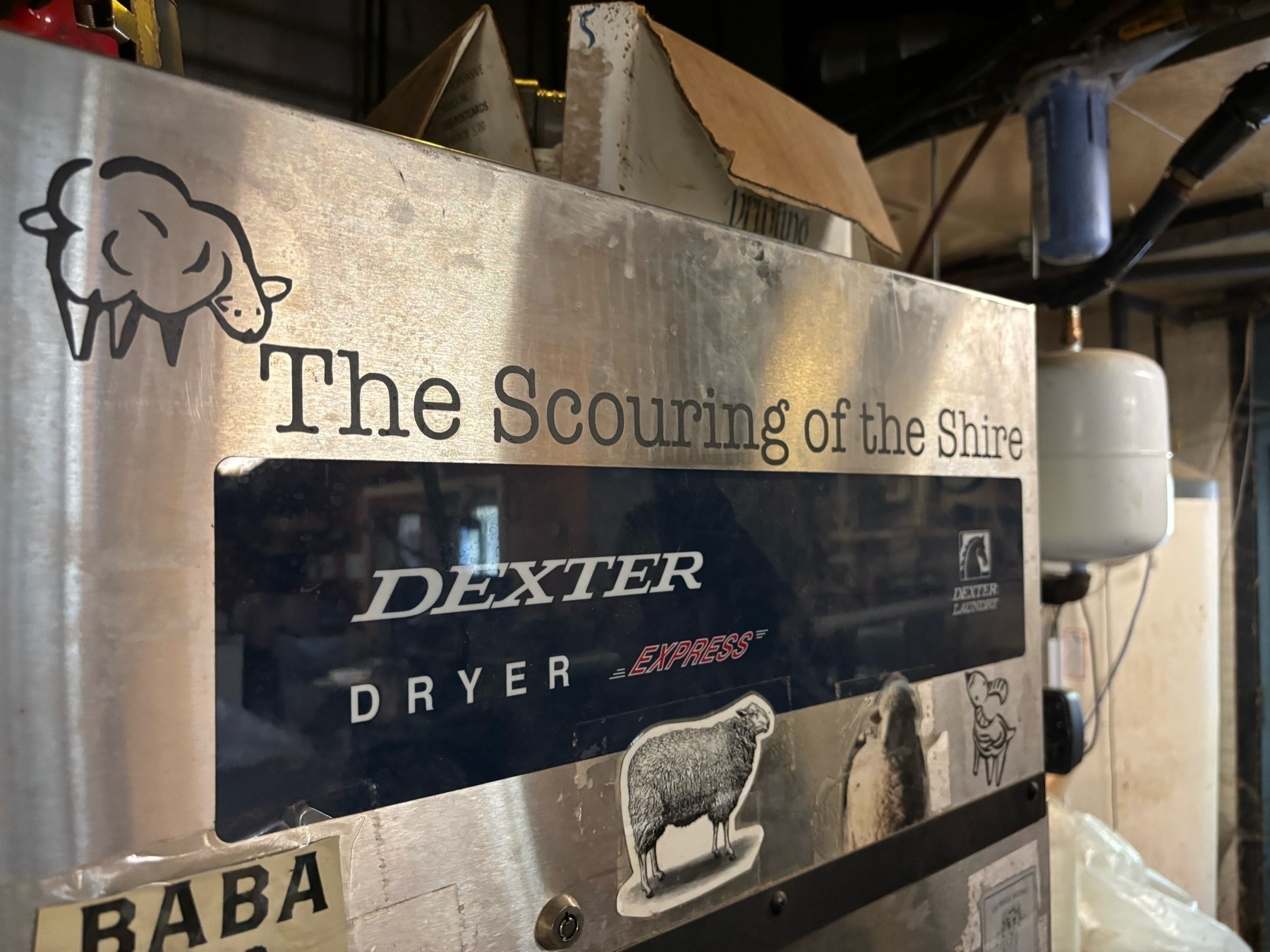 The top corner of a metal dryer.  There are some sheep stickers, a "Dexter Dryer" black label, and the text "The Scouring of the Shire"