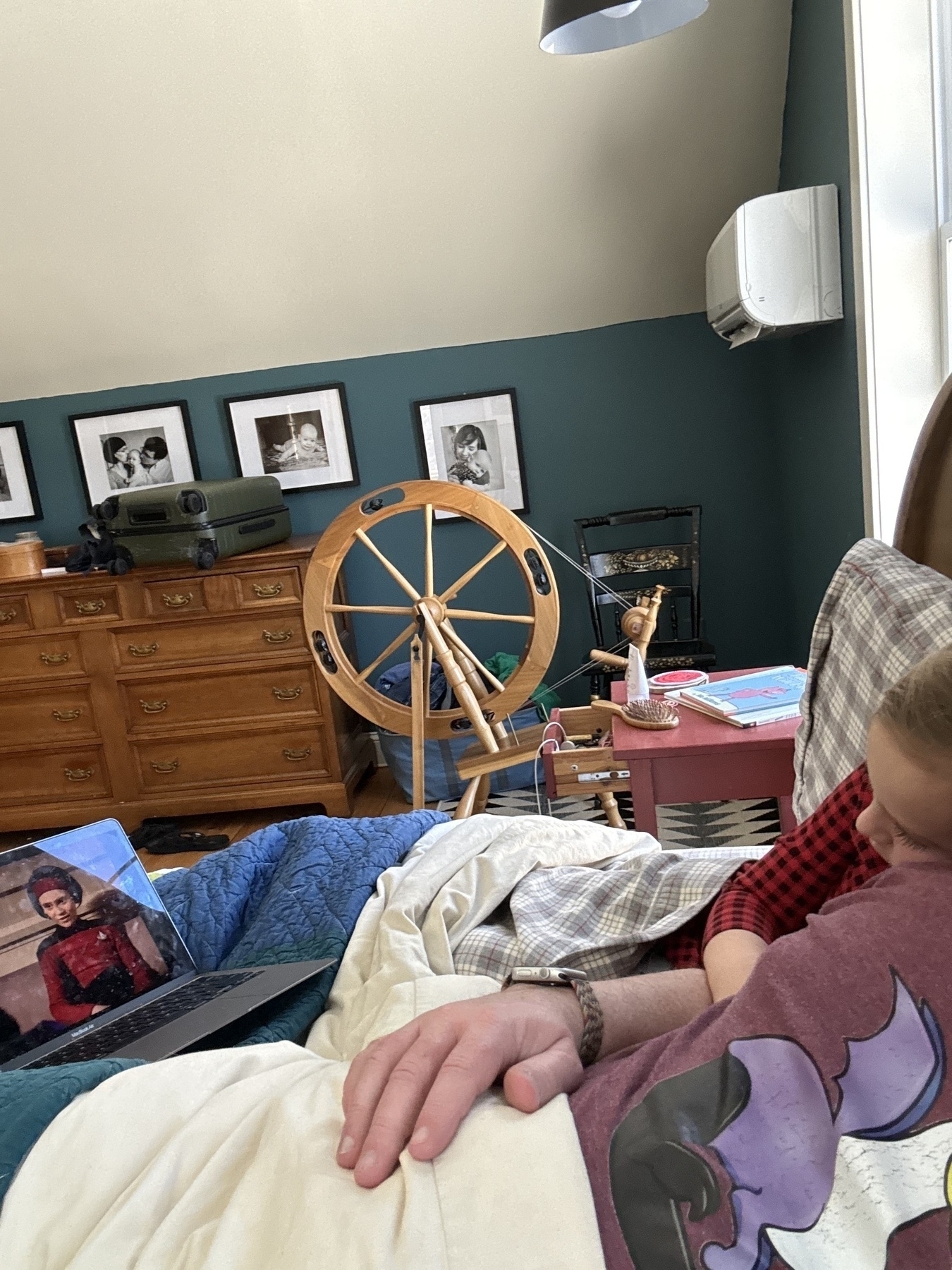 Prominent in the center of the image is a spinning wheel and some family photos. On one side. A computer with an image of the child Ro Laren (from TNG episode “Rascals”) on the other, a small blond child snuggled against my shoulder)