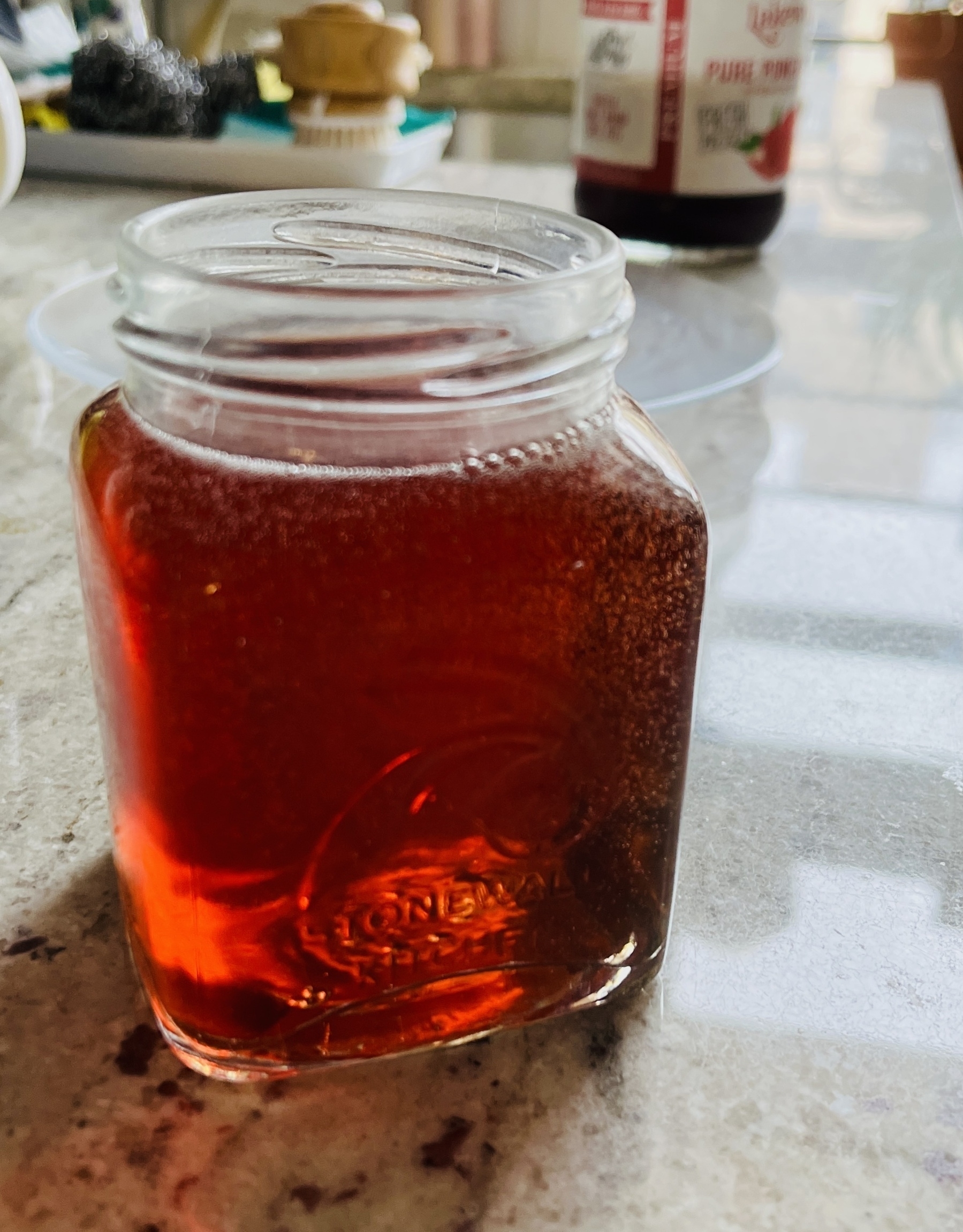 In a jar, red liquid. It is pomegranate juice with a few bubbles from carbonation in it.