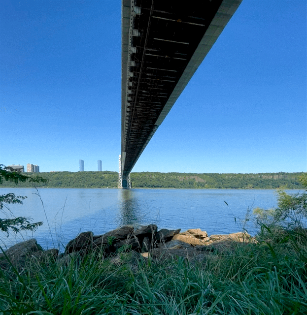 A picture of the Hudson River, flowing calmly under the GW bridge, directly and far above