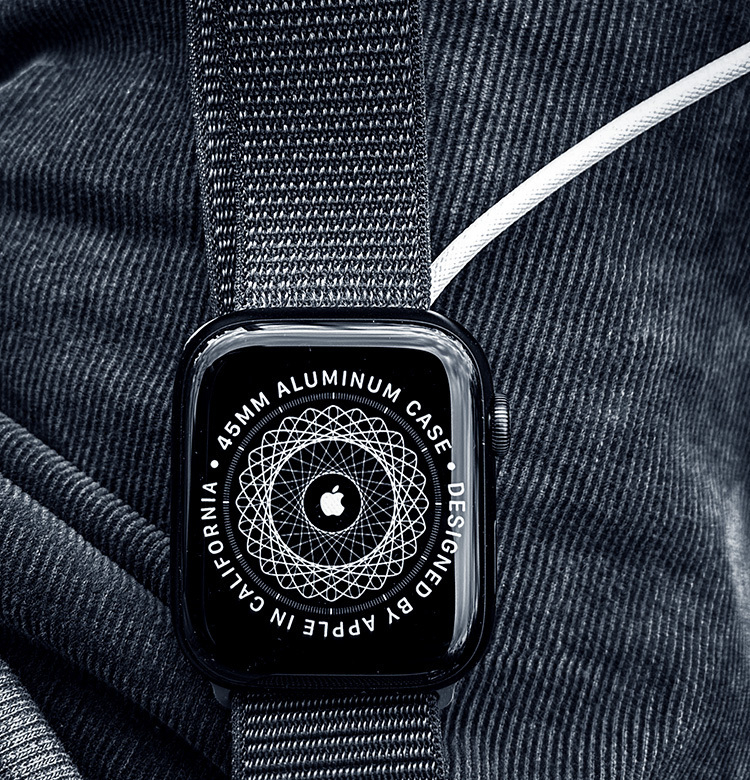 An apple watch during its setup stage, with a white charging cable at the side