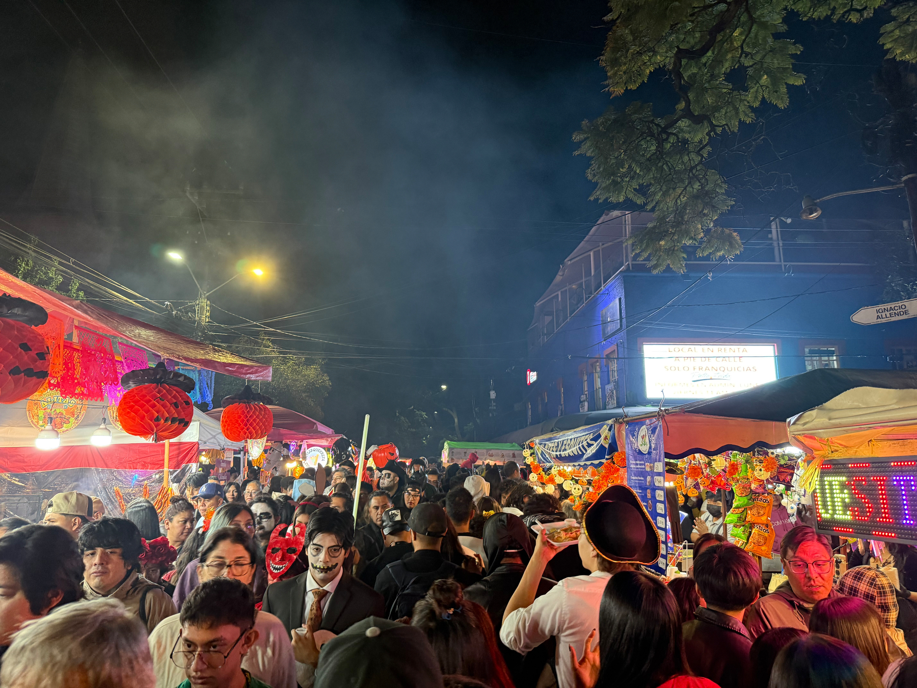 Auto-generated description: A bustling night market is filled with people, colorful lights, and festive decorations.