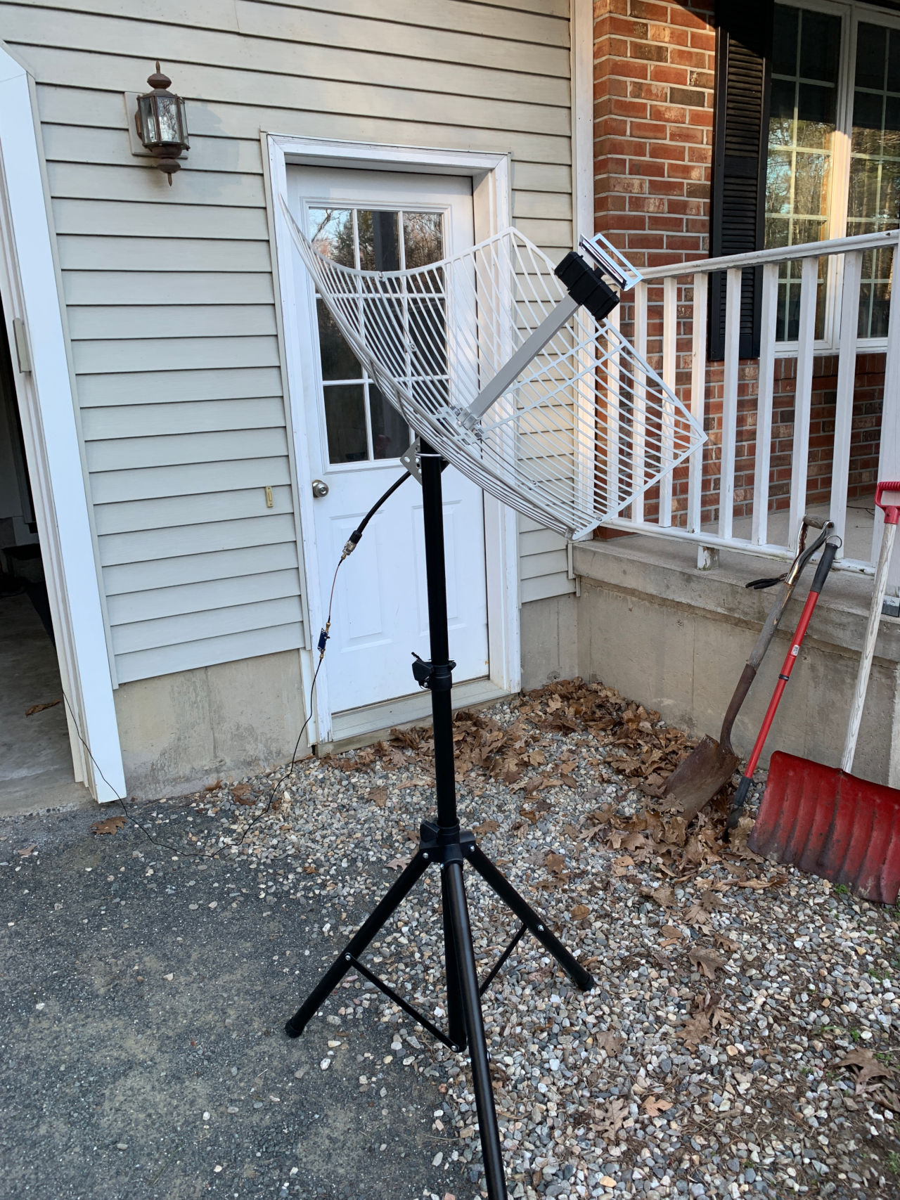 Photograph of a satellite dish mounted on a tripod pointing towards the sky.
