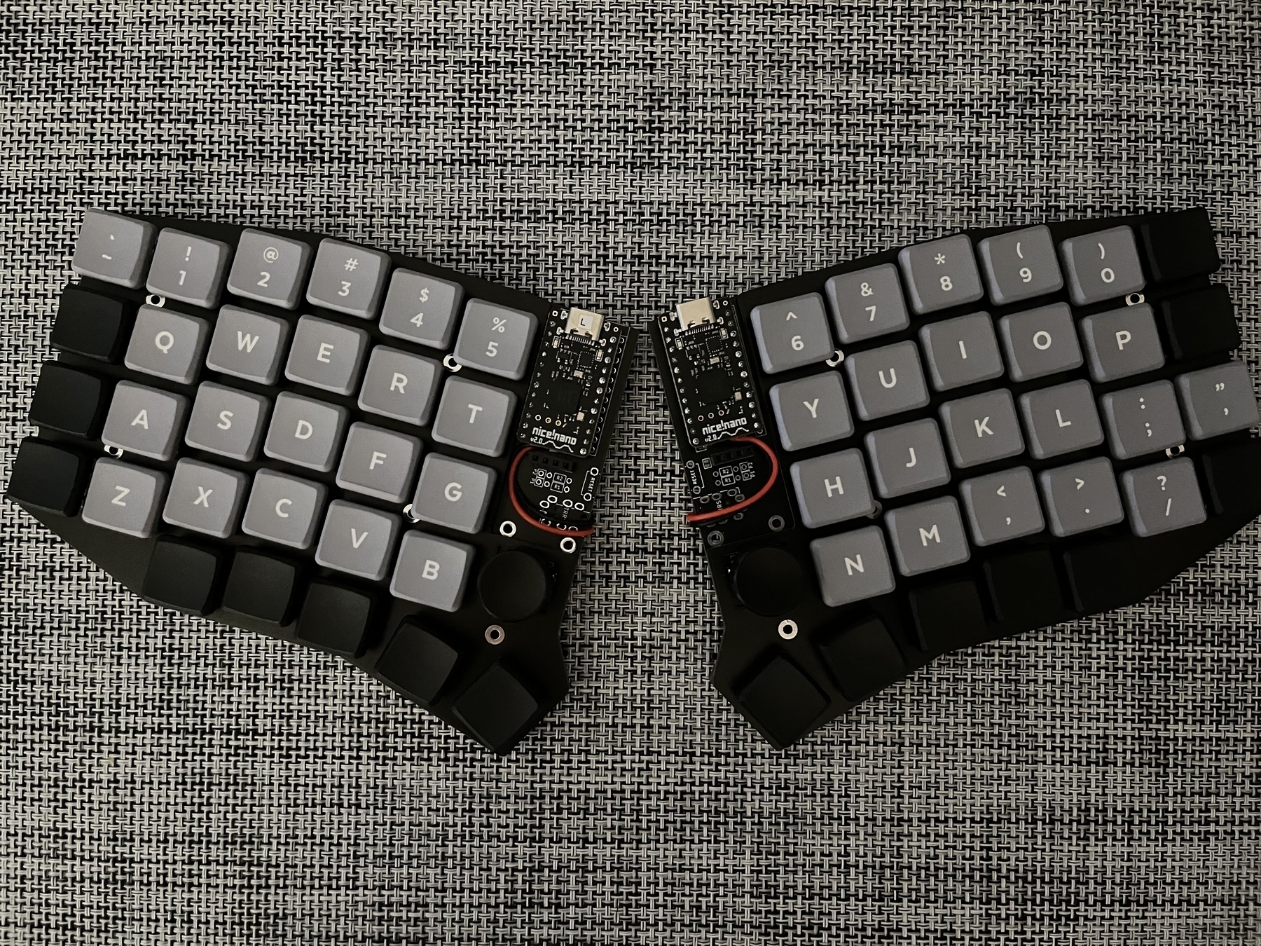 Photo of a split mechanical keyboard with grey alphanumeric keycaps and blank, black modifier keycaps.