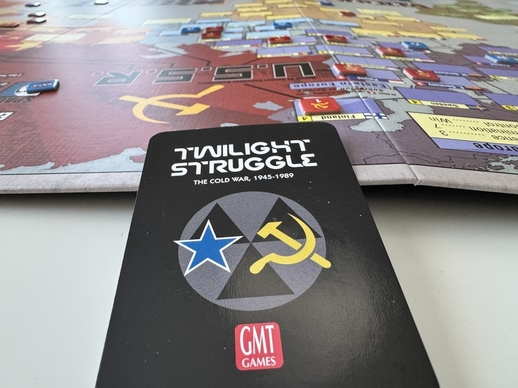 A Twilight Struggle board game card is placed in the foreground with the game board and pieces visible in the background.