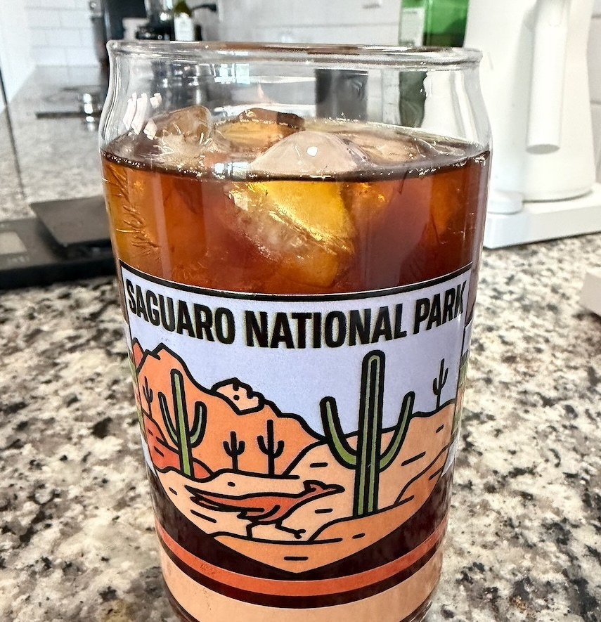 A glass of iced coffee with a Saguaro National Park design sits on a granite countertop.