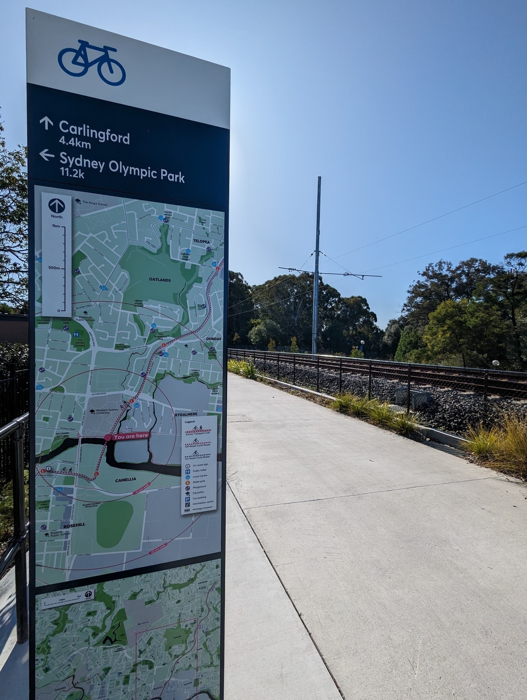 A wayfinding sign at the start of the brand new Rydalmere to Carlingford bike path. In the background is the new light rail line, due to open in 2024.