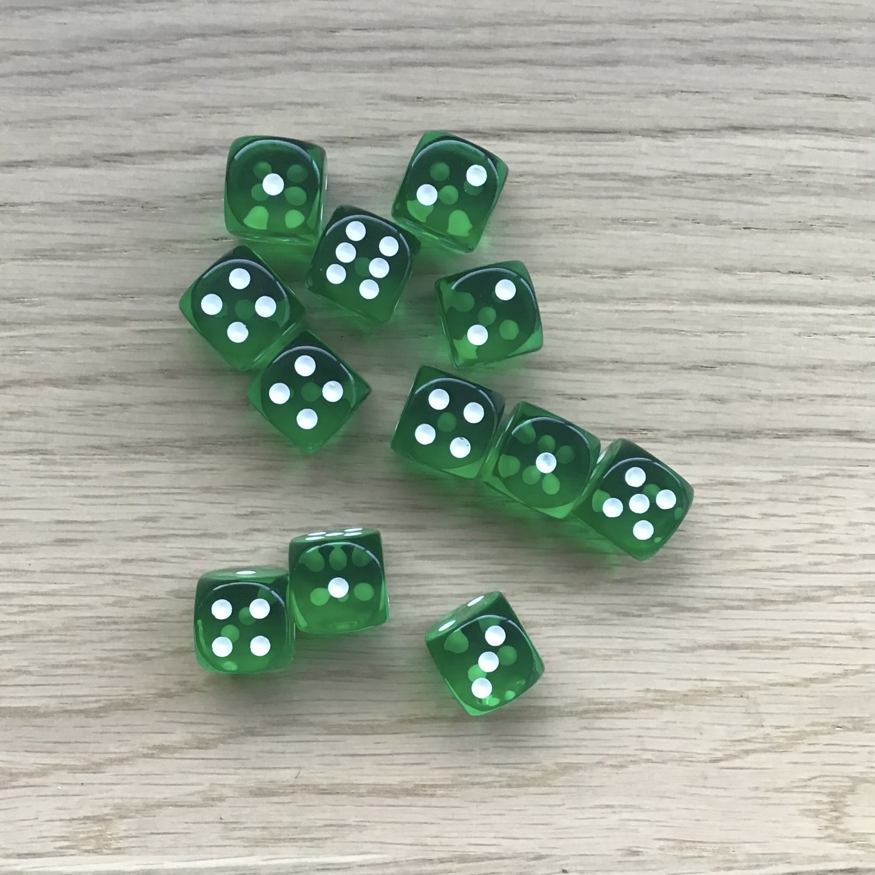 Twelve green six-sided dice on a wooden surface.