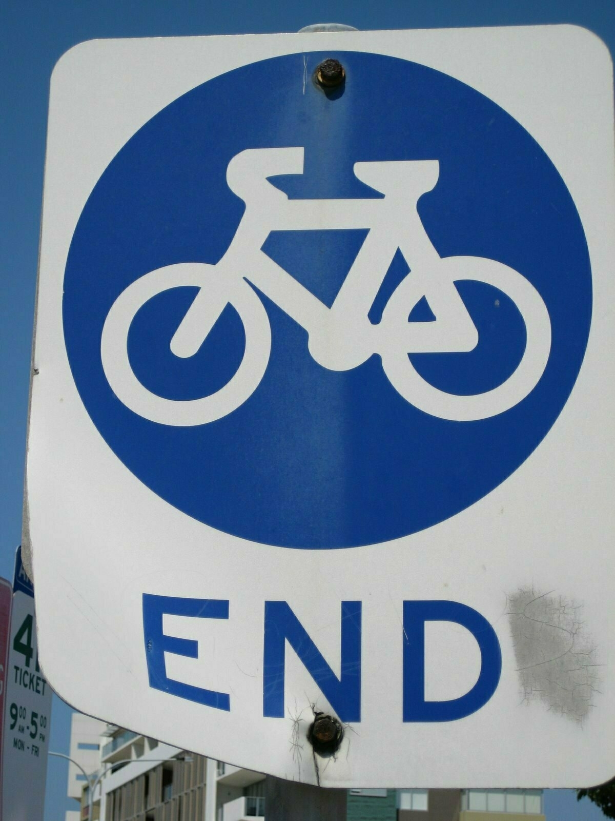 A blue and white road sign marks the end of a bicycle path.