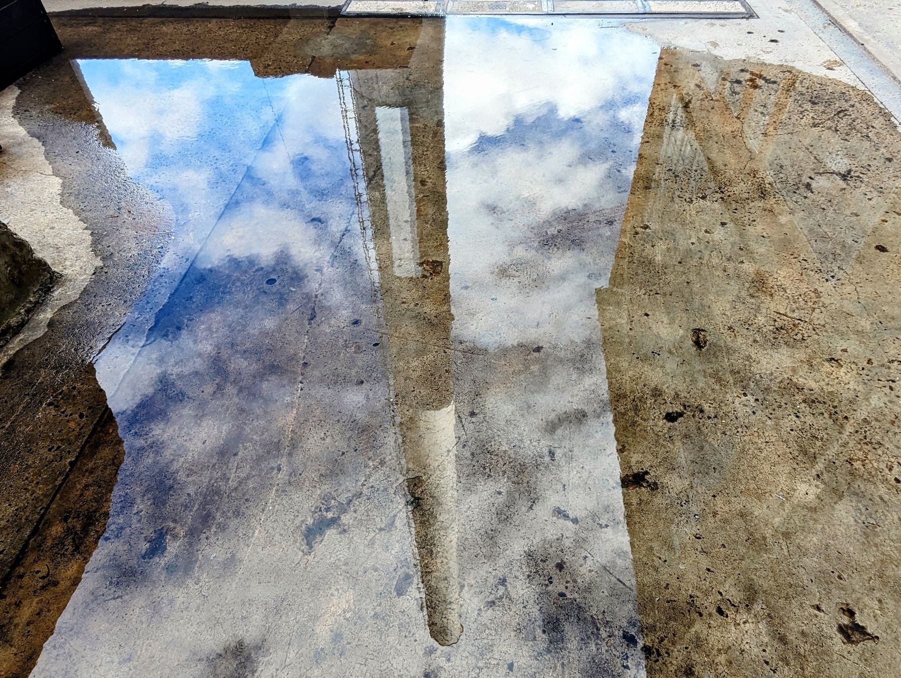 A tall power station chimney, reflected upside down in a puddle.