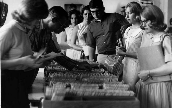 a group of students trying to register for university courses using trays of punched cards in 1968