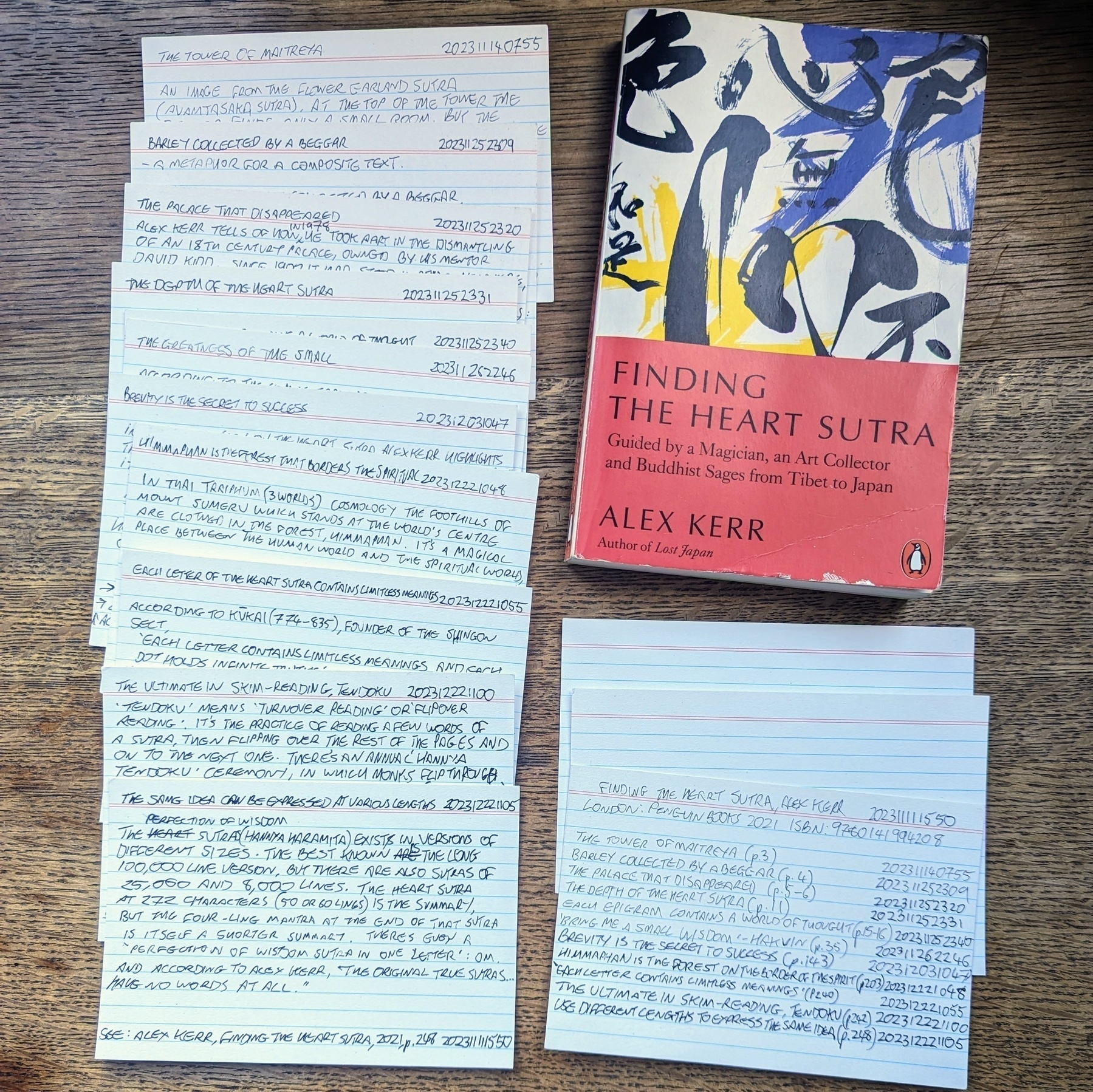 A book on a table surrounded by hand-written notes on index cards