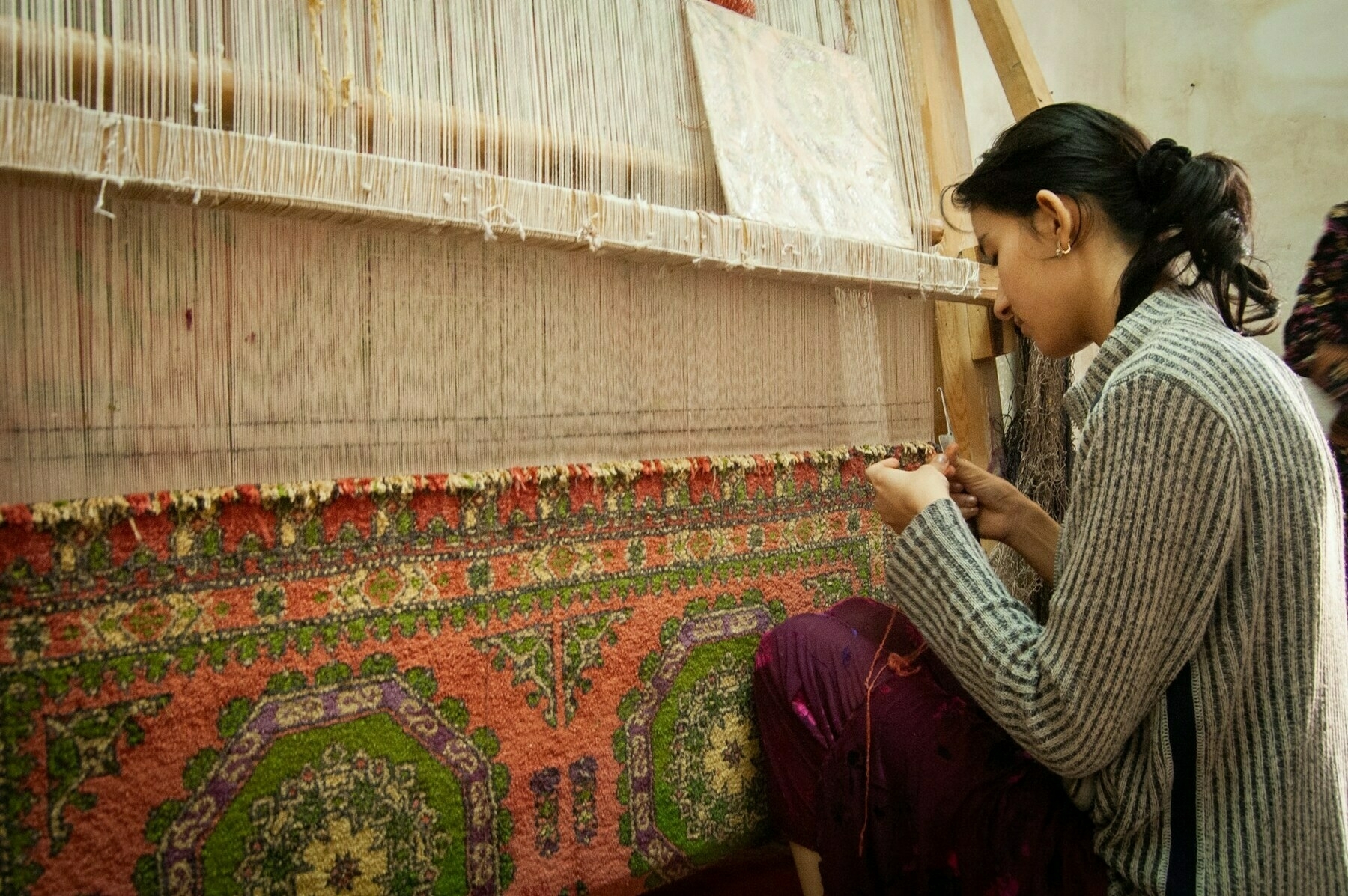 a woman is weaving a carpet