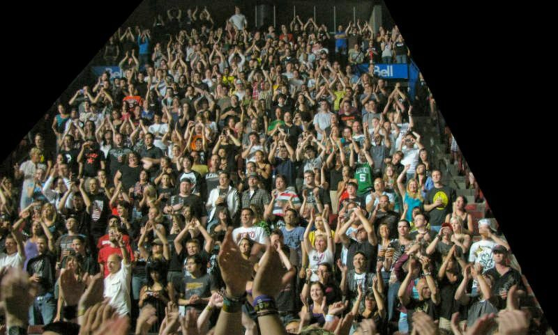 A crowd of 250 people enthusiastically clapping and cheering in an indoor venue.
