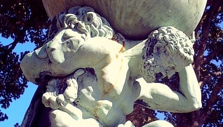 a white plaster statue of Atlas holding a globe on his shoulders