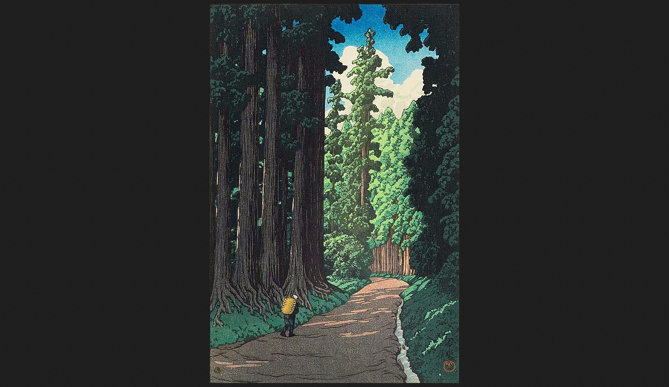 A person with a basket walks along the Nikko Kaido, a path surrounded by towering trees. A woodblock print by Hasui Kawase.