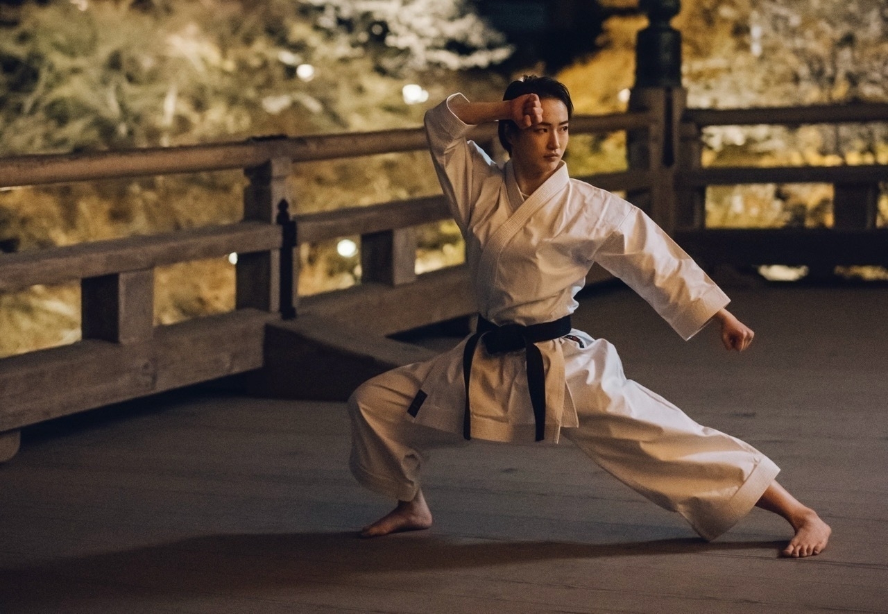 Karate kata champion Kiyou Shimizu in a white gi, posing in a strong stance on the wooden platform at Kiyomizu-dera Temple, Kyoto.