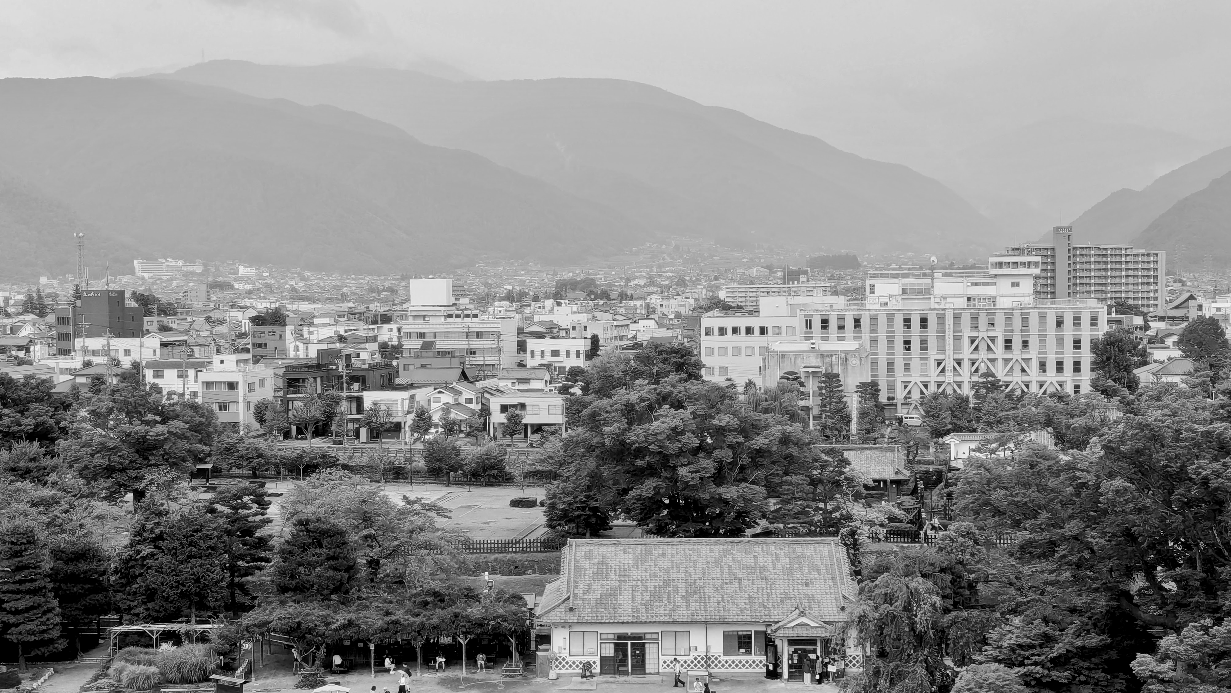The Matsumoto cityscape with a mix of modern and traditional buildings is set against a backdrop of mountains.