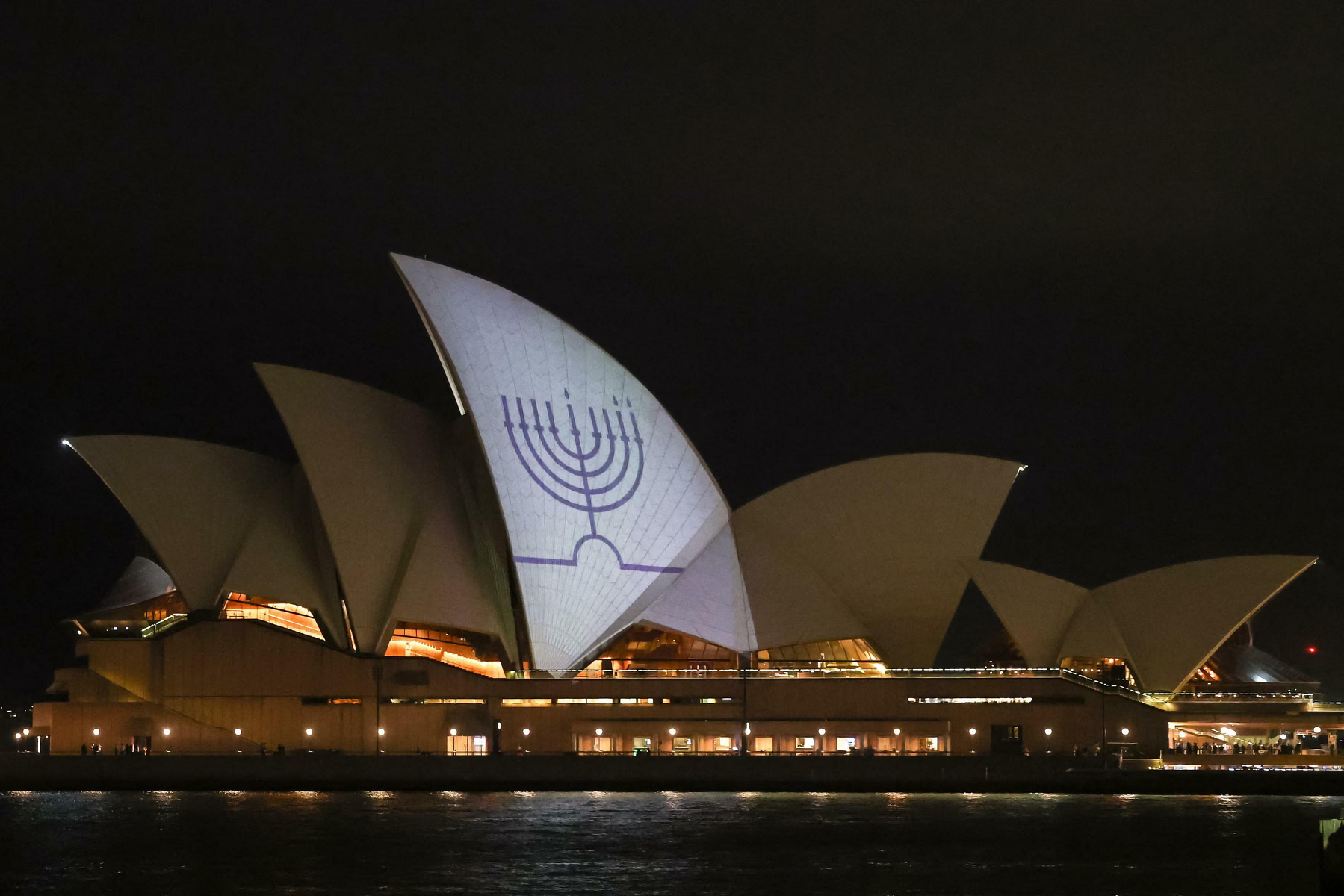 A menorah is projected onto the sails of the Sydney Opera House at night.