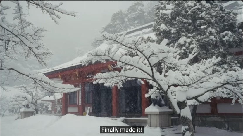 A snowy scene features a traditional Japanese temple building at Kurama-dera, surrounded by snow-covered trees.