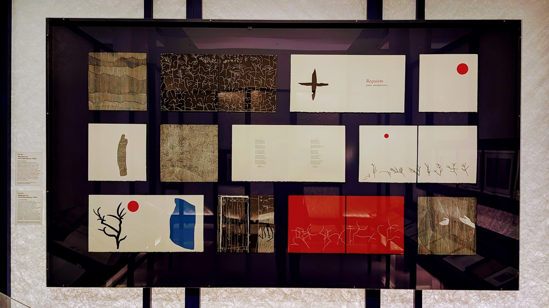 A display case showcases pages from an artist&rsquo;s book, featuring red, black, and white colors.