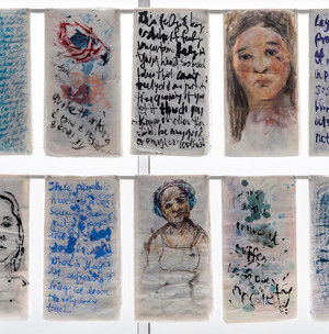 A display features hanging translucent fabric panels with watercolor portraits and handwritten text in various styles and colors.