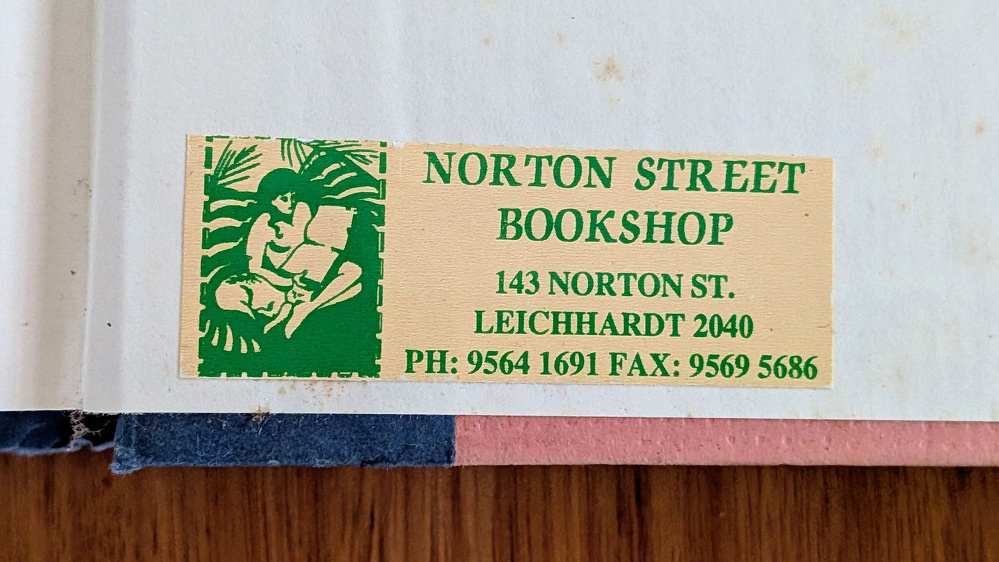 A label for Norton Street Bookshop in Leichhardt, including an image of a woman reading while sitting beside a cat, is displayed on a book page.