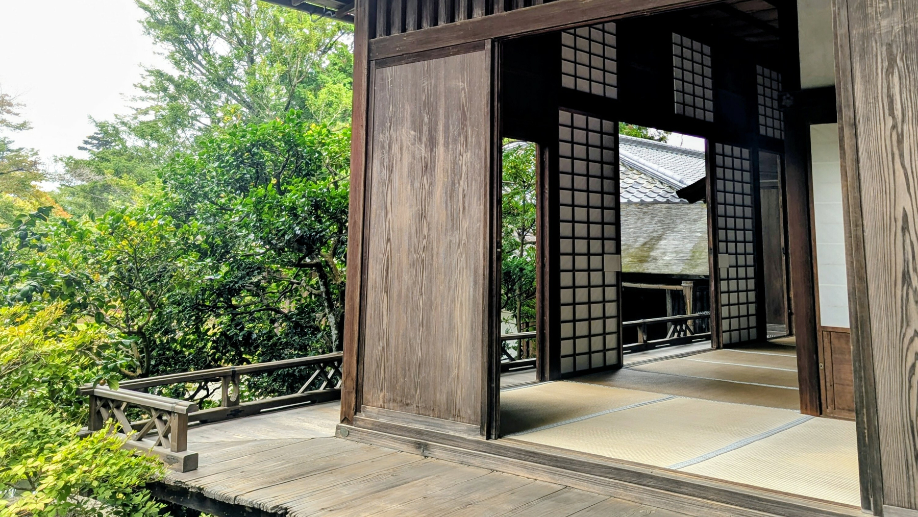 A traditional Japanese-style room with shoji screens opens up to an engawa porch with a lush garden view.