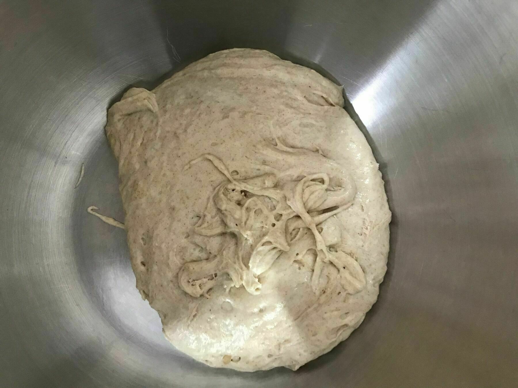Some bread dough in a stainless steel bowl.