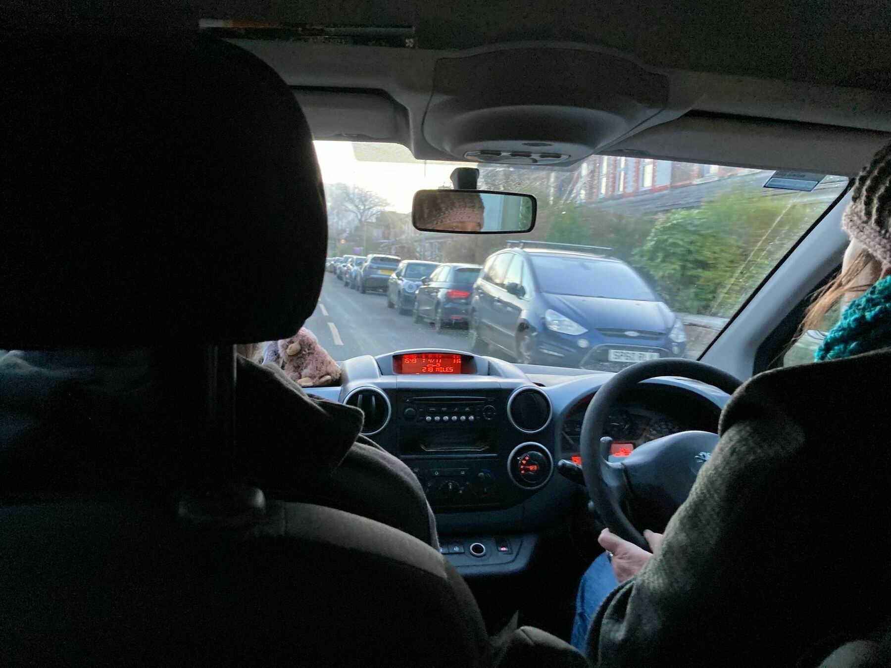 view from the rear seat of a car travelling along a residential street in the UK. 
