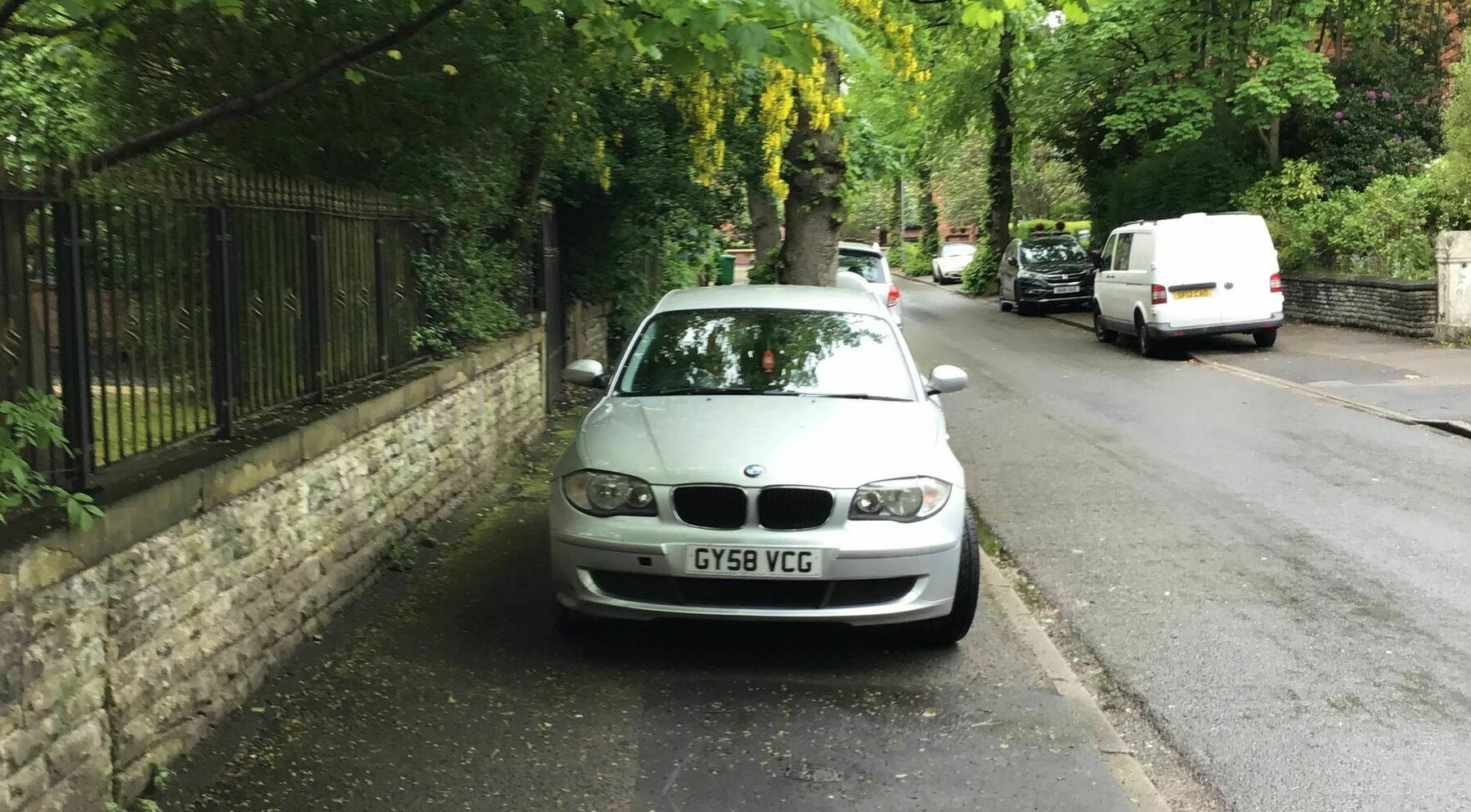 A car parked on a pavement on a quiet suburban street.