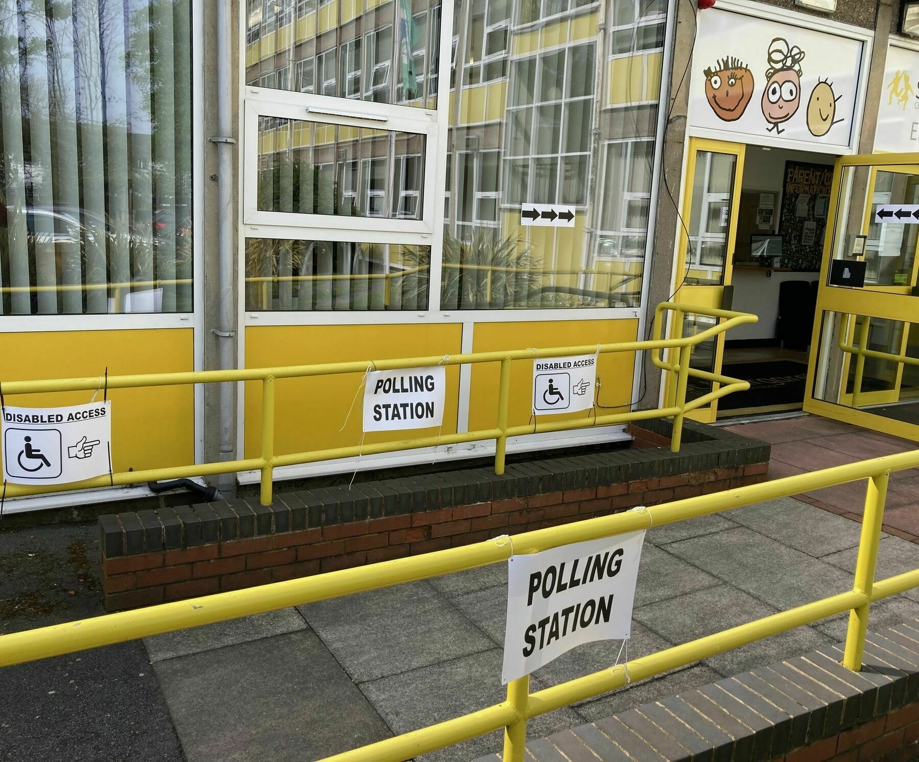 Entrance to a UK Polling Station in a school building. Signs and arrows direct you into the open entrance.