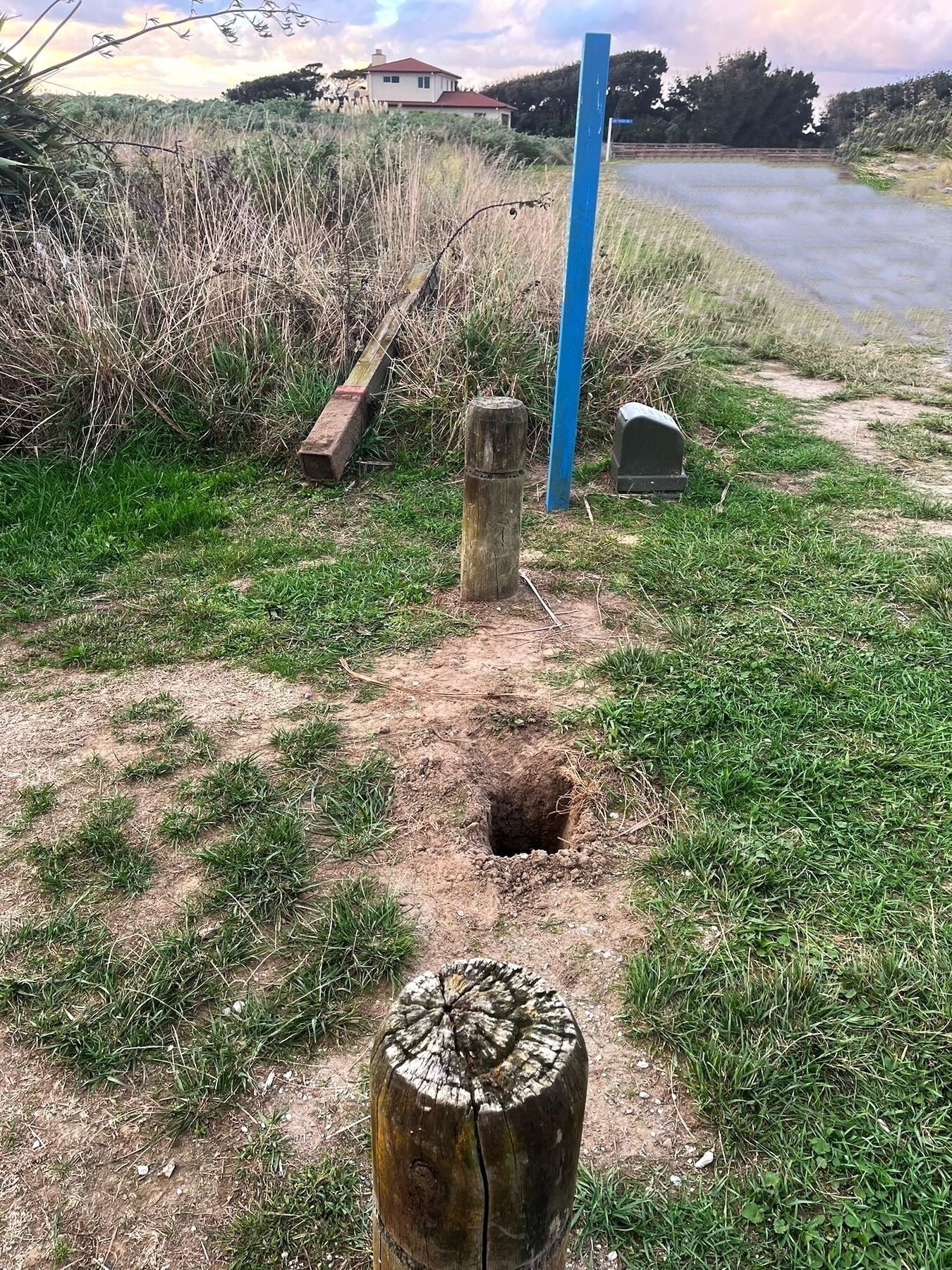 Large marker post has been removed and discarded, and a large hole remains in the ground. 