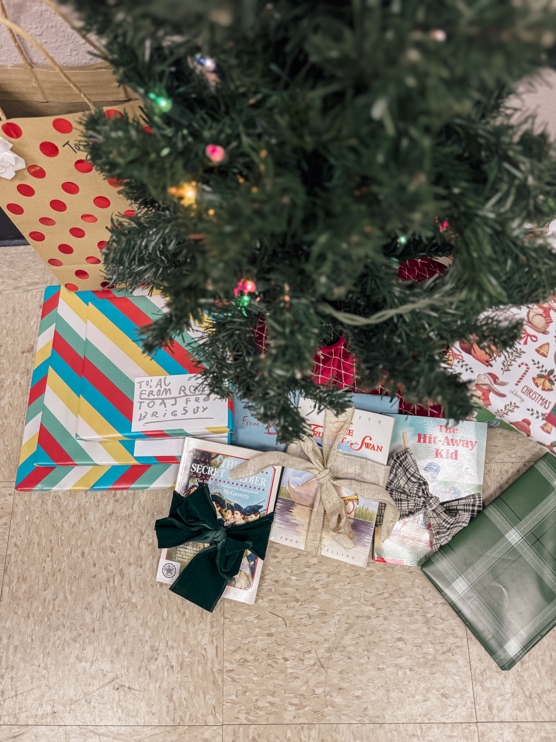 Wrapped books beneath a small Christmas tree